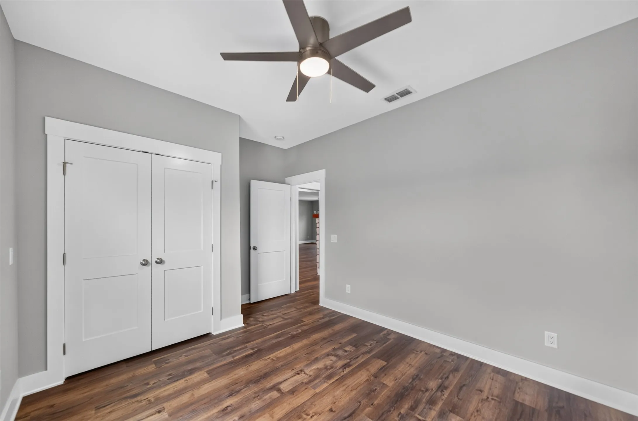 Room featuring wood-finish flooring, light grey walls, and a contemporary ceiling fan with integrated lighting