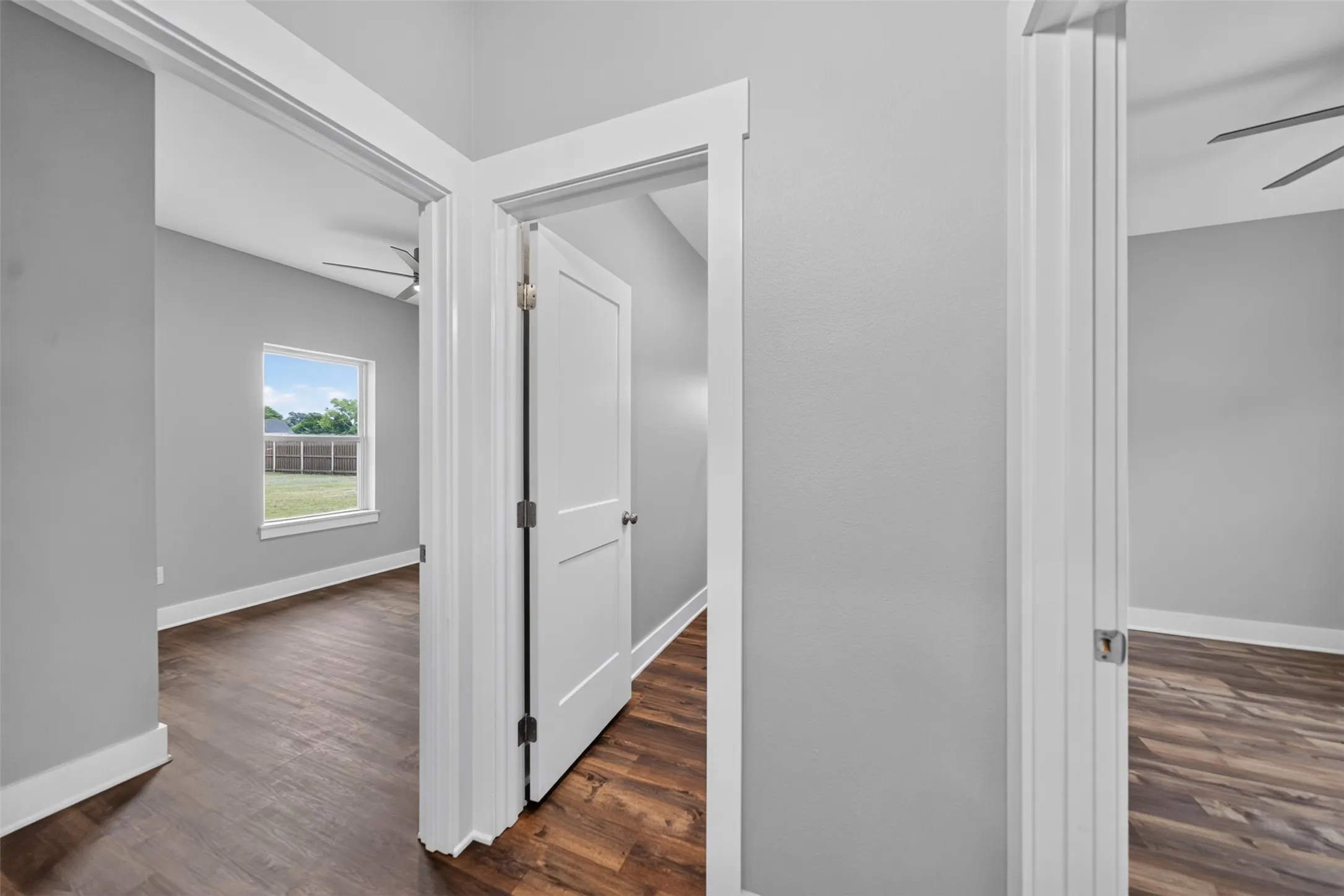 Interior hallway with wood-finish flooring, light grey painted walls, and white trim
