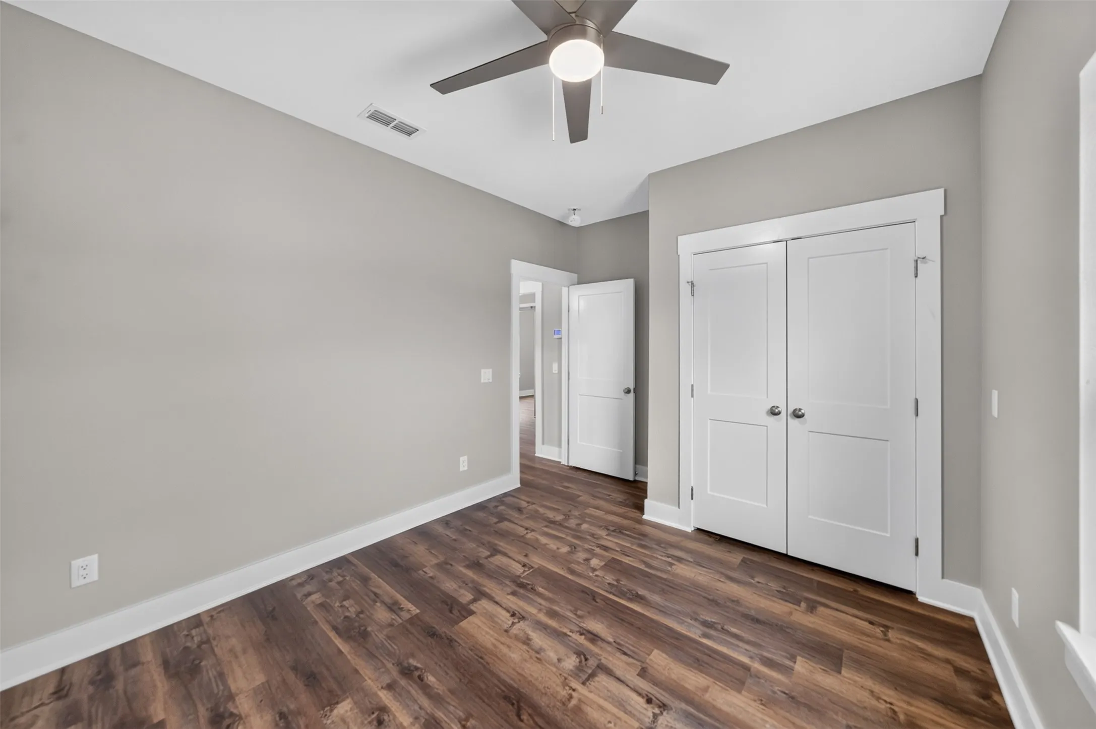 Room featuring wood-finish flooring, light grey painted walls, and white baseboards