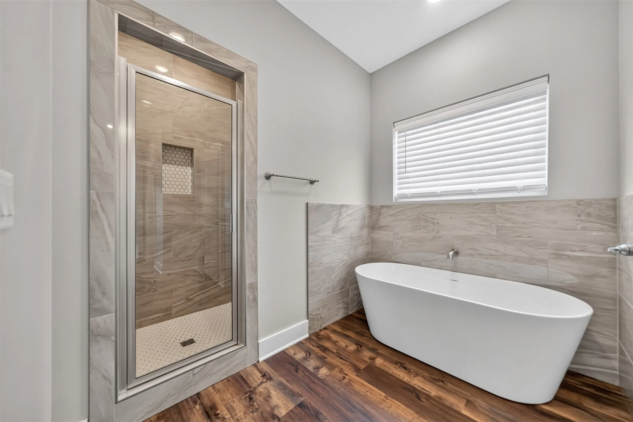 Contemporary bathroom with a frameless glass shower enclosure, a freestanding oval tub, and wood-finish flooring