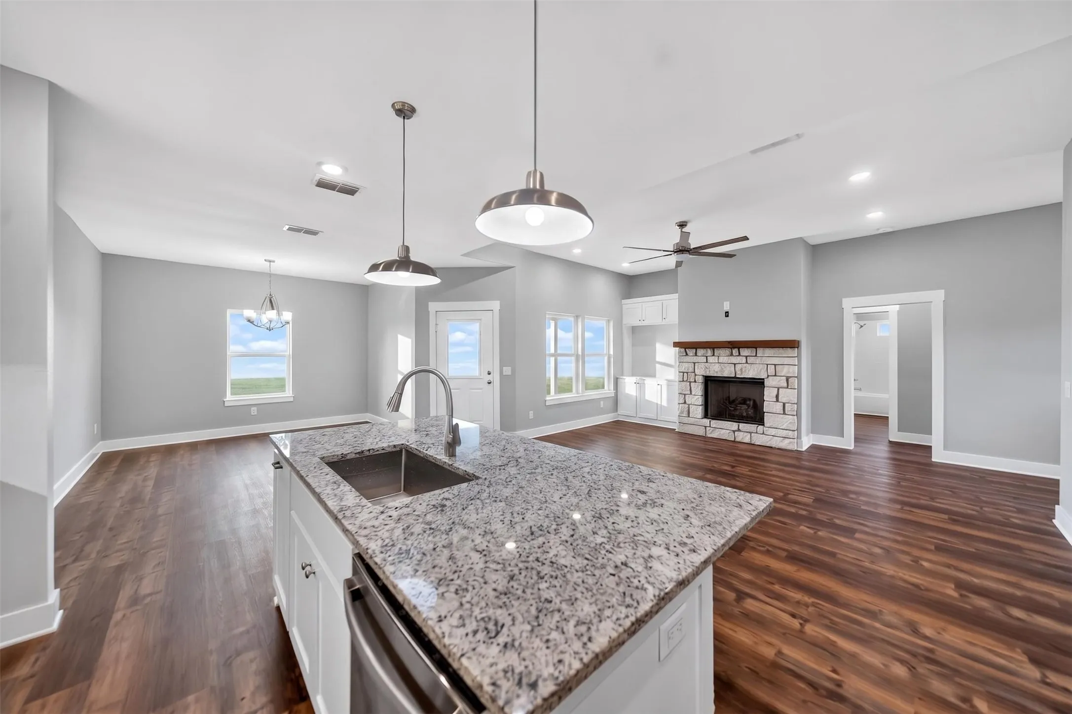 Gourmet kitchen island with granite countertop and undermount sink, complemented by pendant lighting