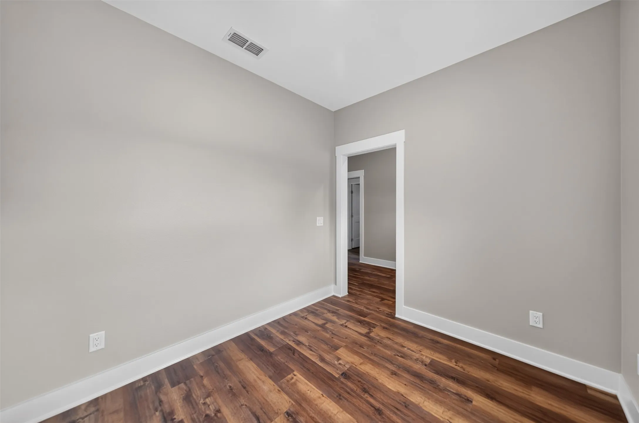 Room featuring wood-finish flooring, light neutral wall paint, and white trim