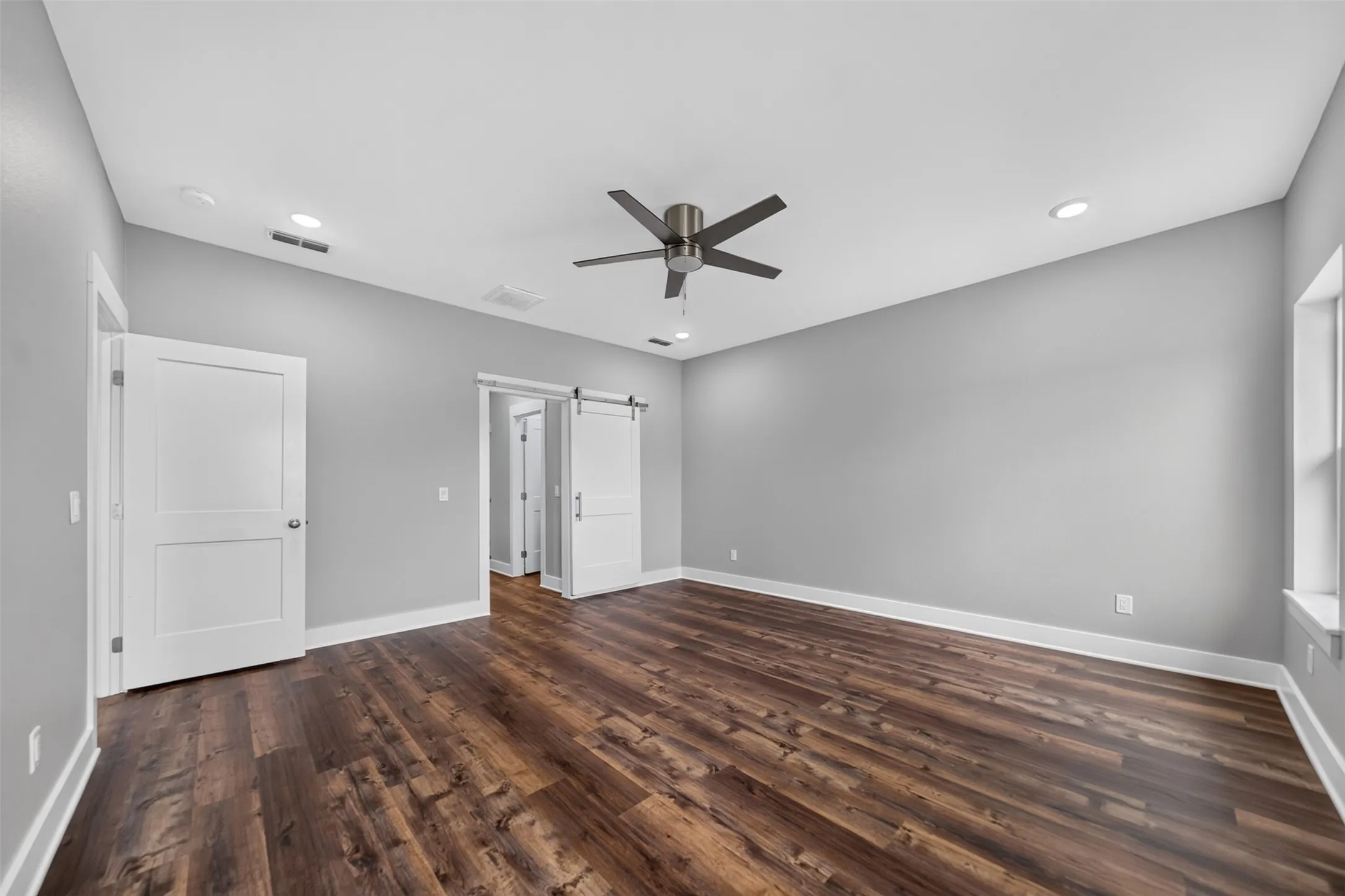 Spacious room featuring wood-finish flooring, light grey walls, and white trim