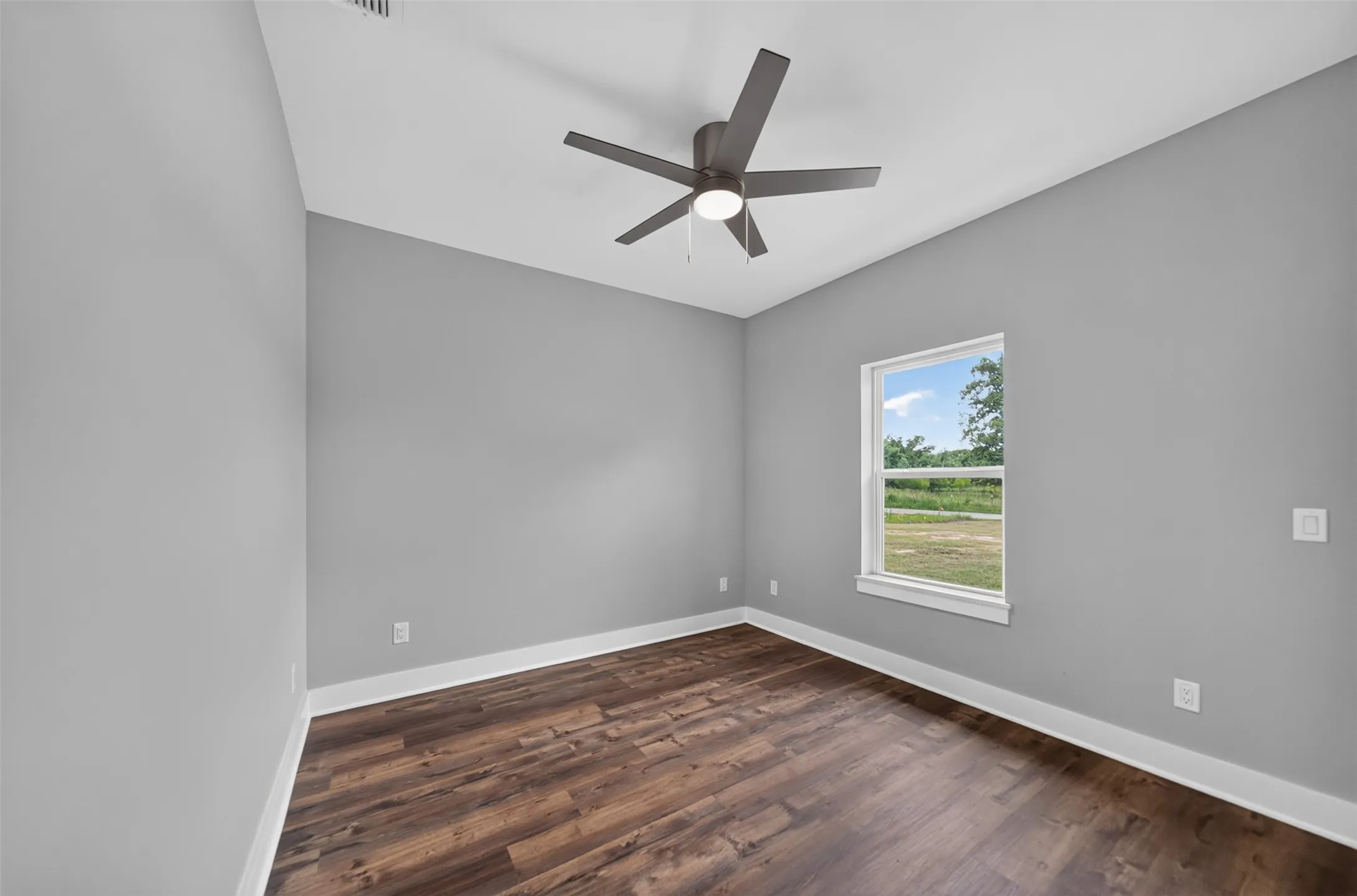 Inviting room featuring a modern ceiling fan with integrated lighting, wood-finish flooring, and a window with white trim