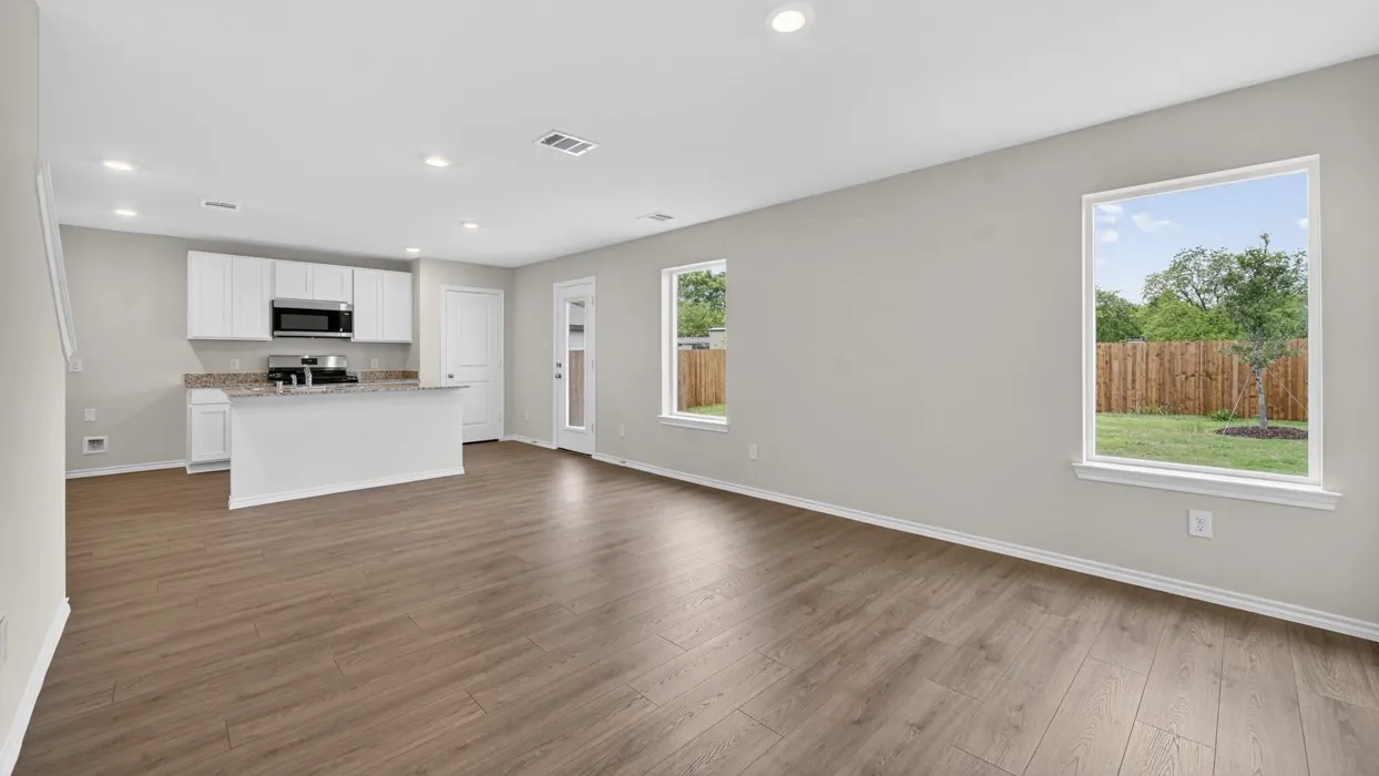 Open-concept living area featuring wood-finish flooring, recessed lighting, and a kitchen island with stone countertops
