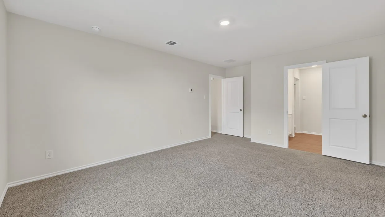 Spacious interior room featuring light gray carpeting, white baseboards, and neutral wall paint