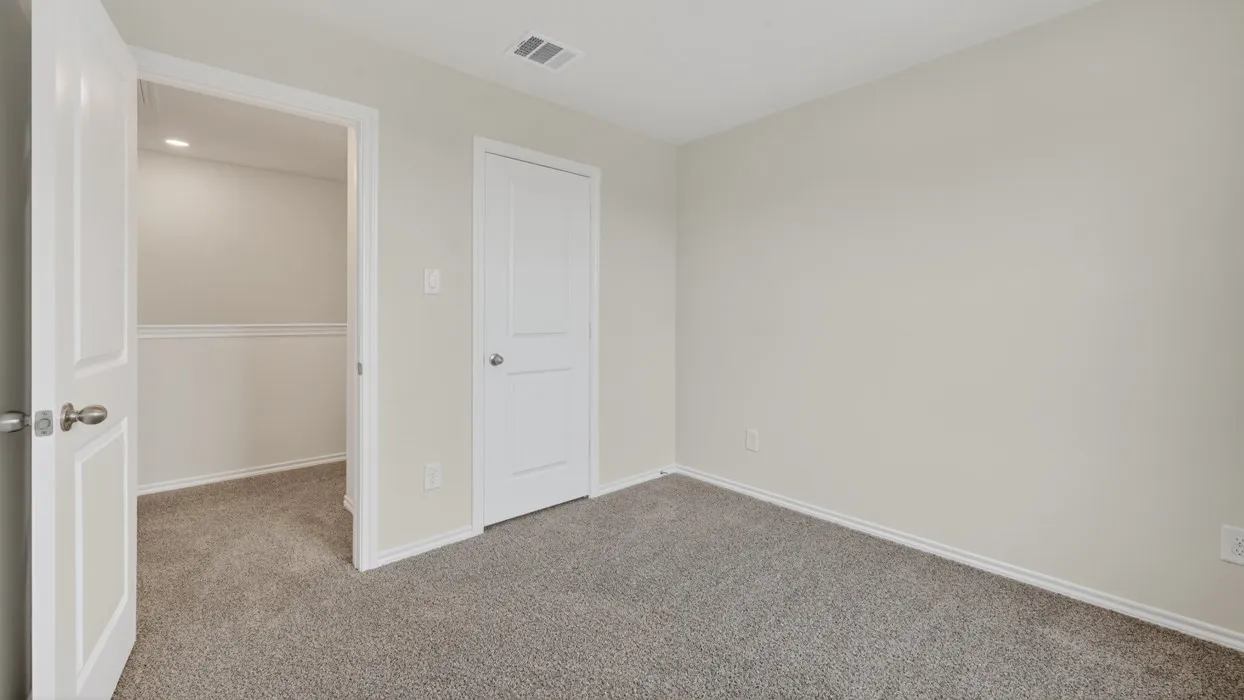 Carpeted room with light neutral walls, white trim, and a white paneled door
