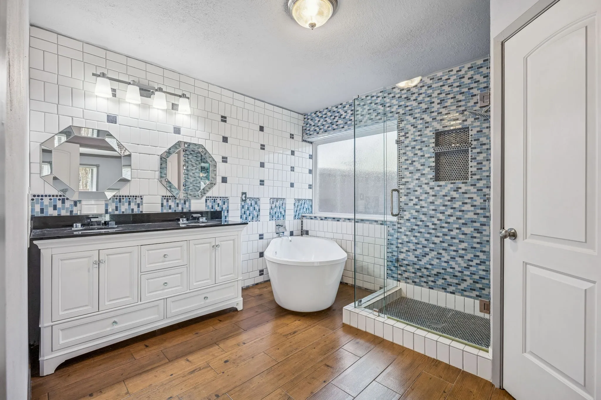 Primary bathroom has a frameless shower, freestanding tub and double vanity. It has a large closet for a home built in the 1990s.