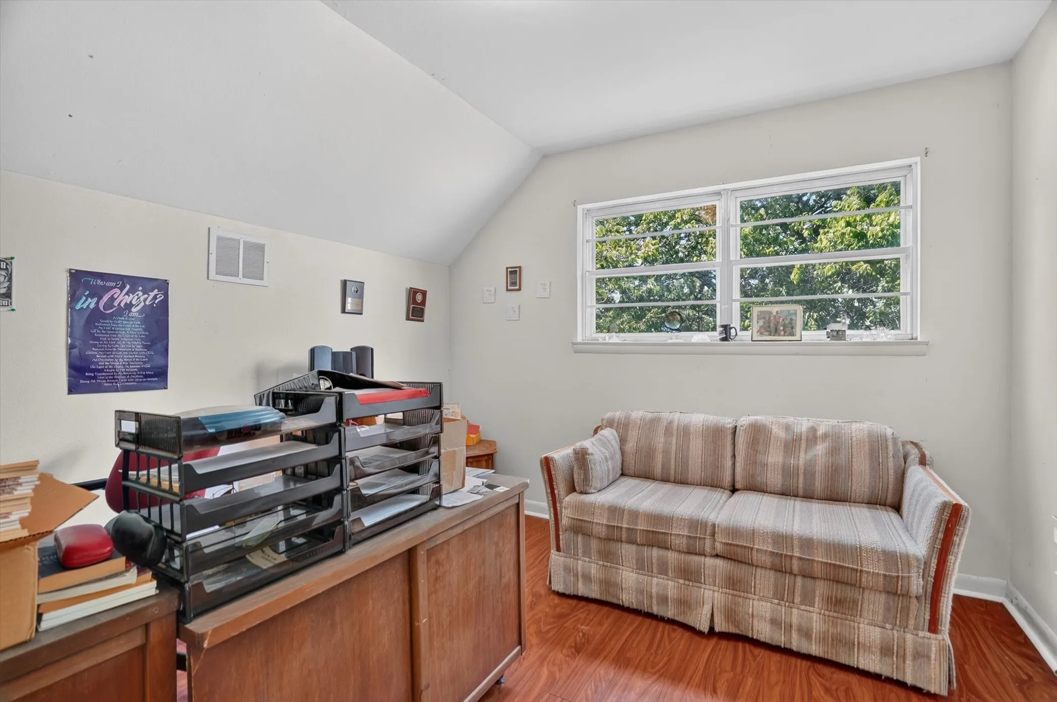 Room with wood-finish flooring, a white vaulted ceiling, and white painted walls