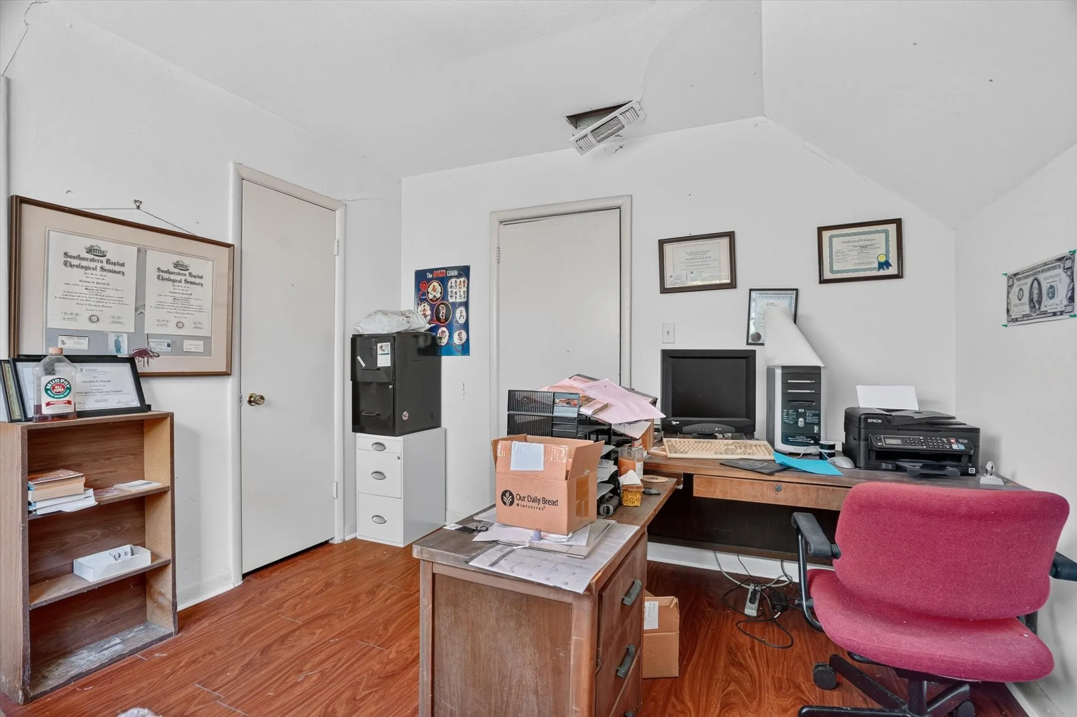 Room featuring wood-finish flooring, white painted walls, and an angled ceiling