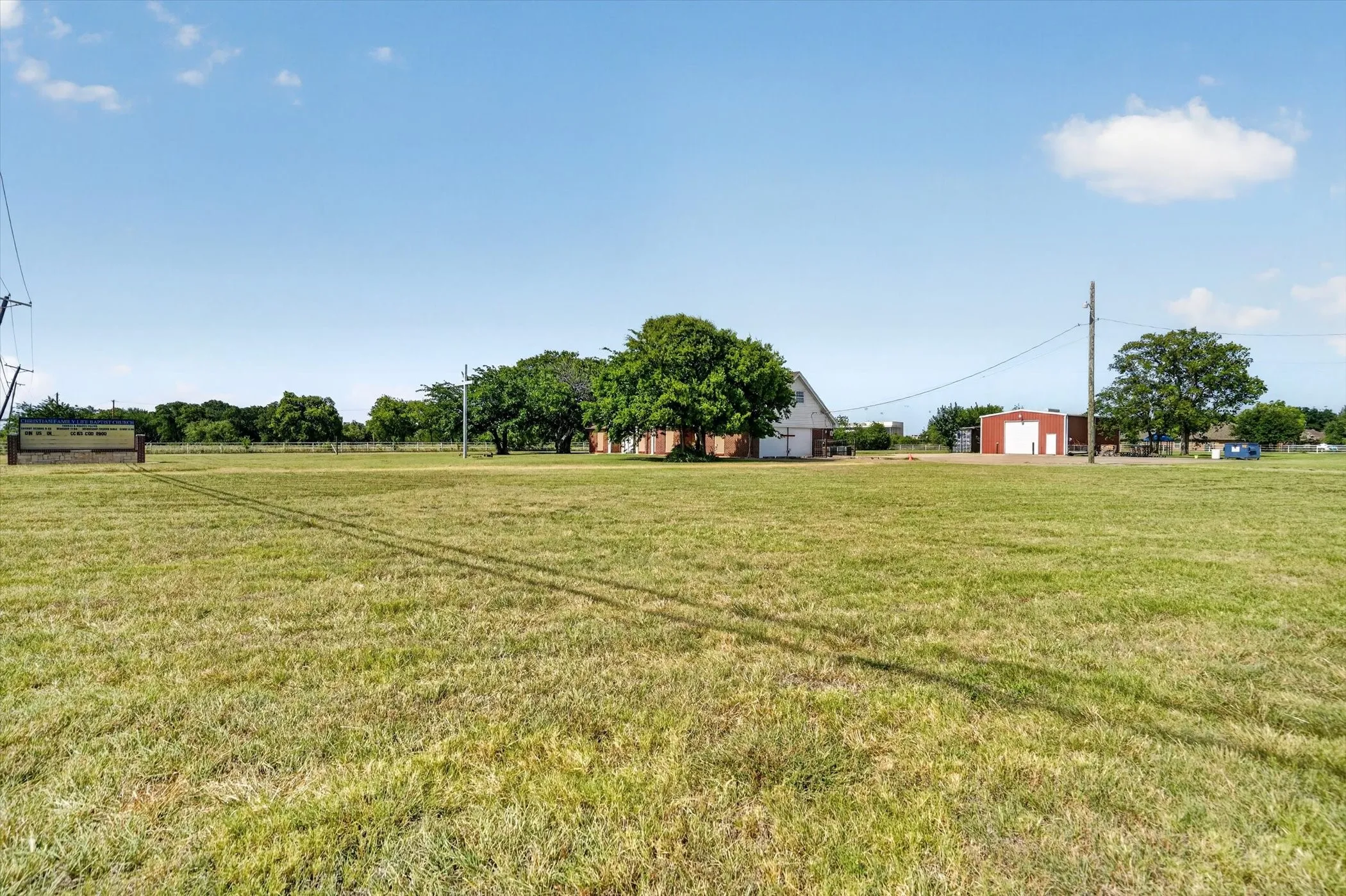 Expansive green acreage featuring a barn with white siding and a brick-front building