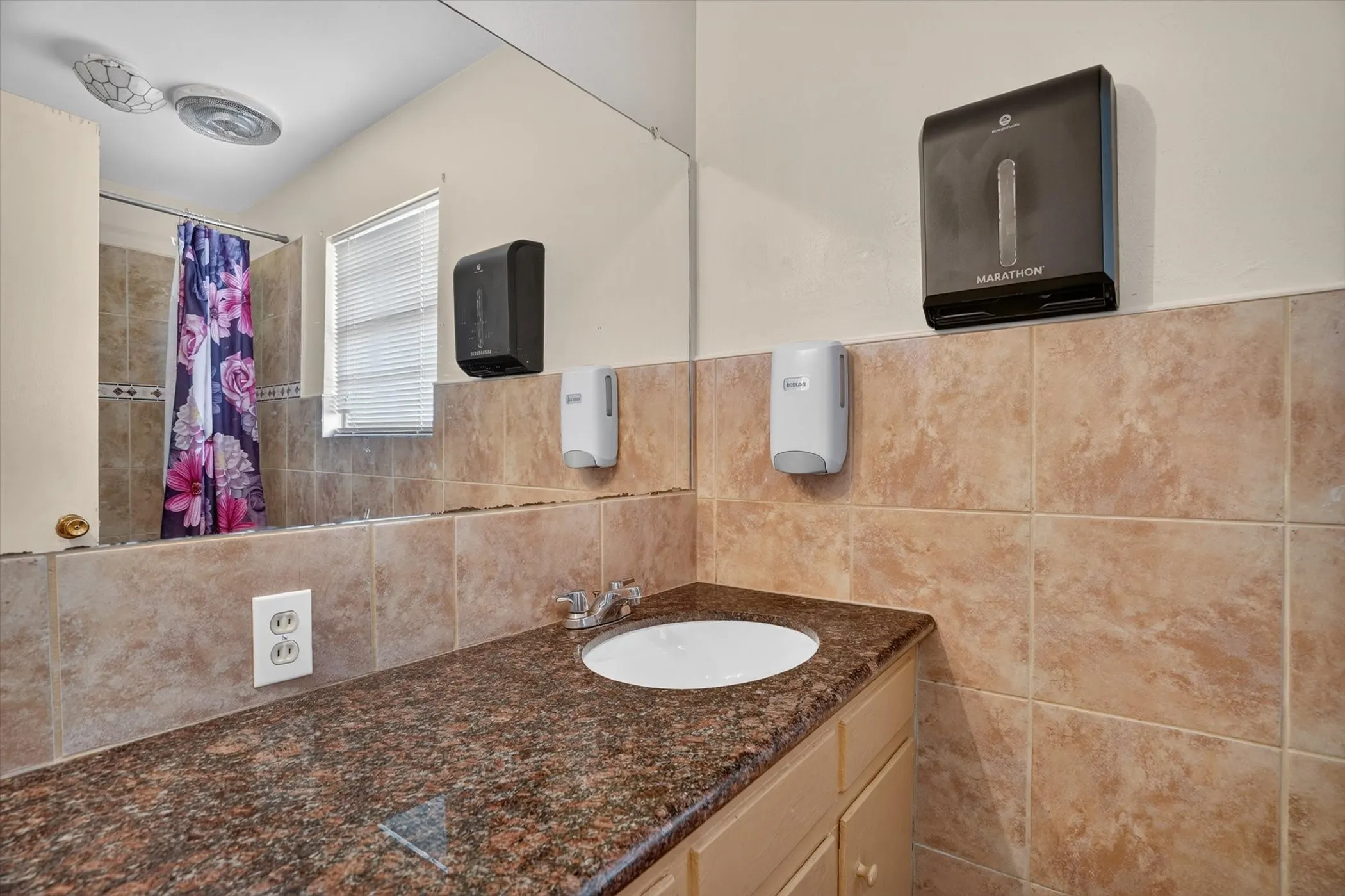 Bathroom vanity with a brown granite-finish countertop, undermount sink, and chrome-finish faucet