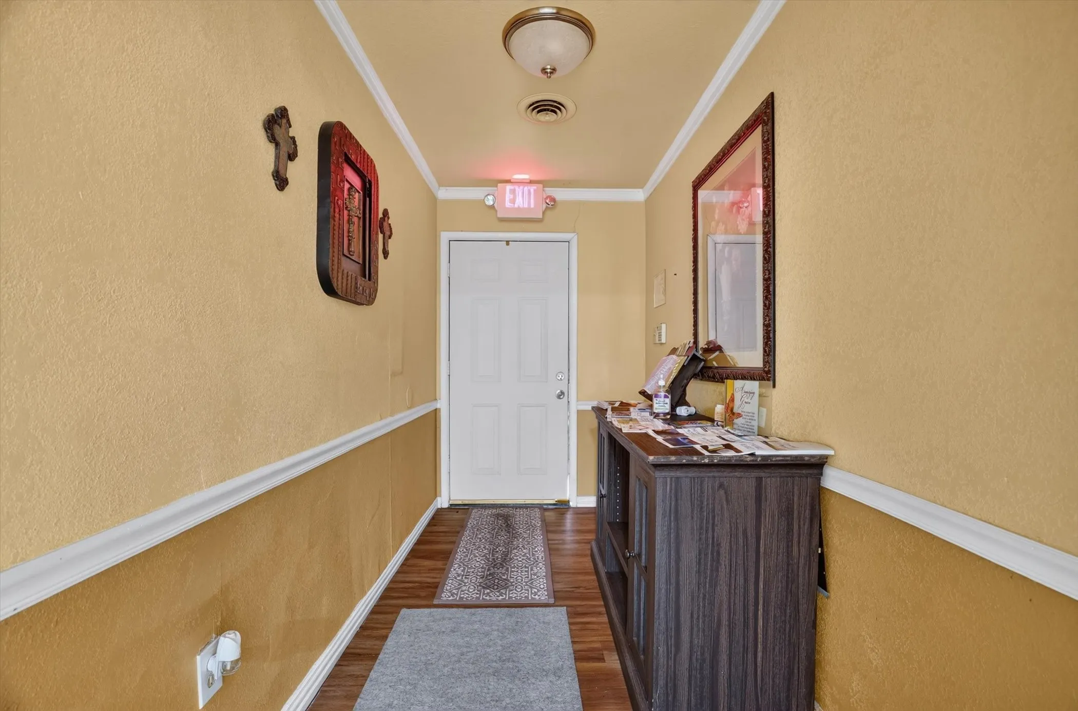 Hallway featuring wood-finish flooring, two-tone walls with chair rail molding, and crown molding