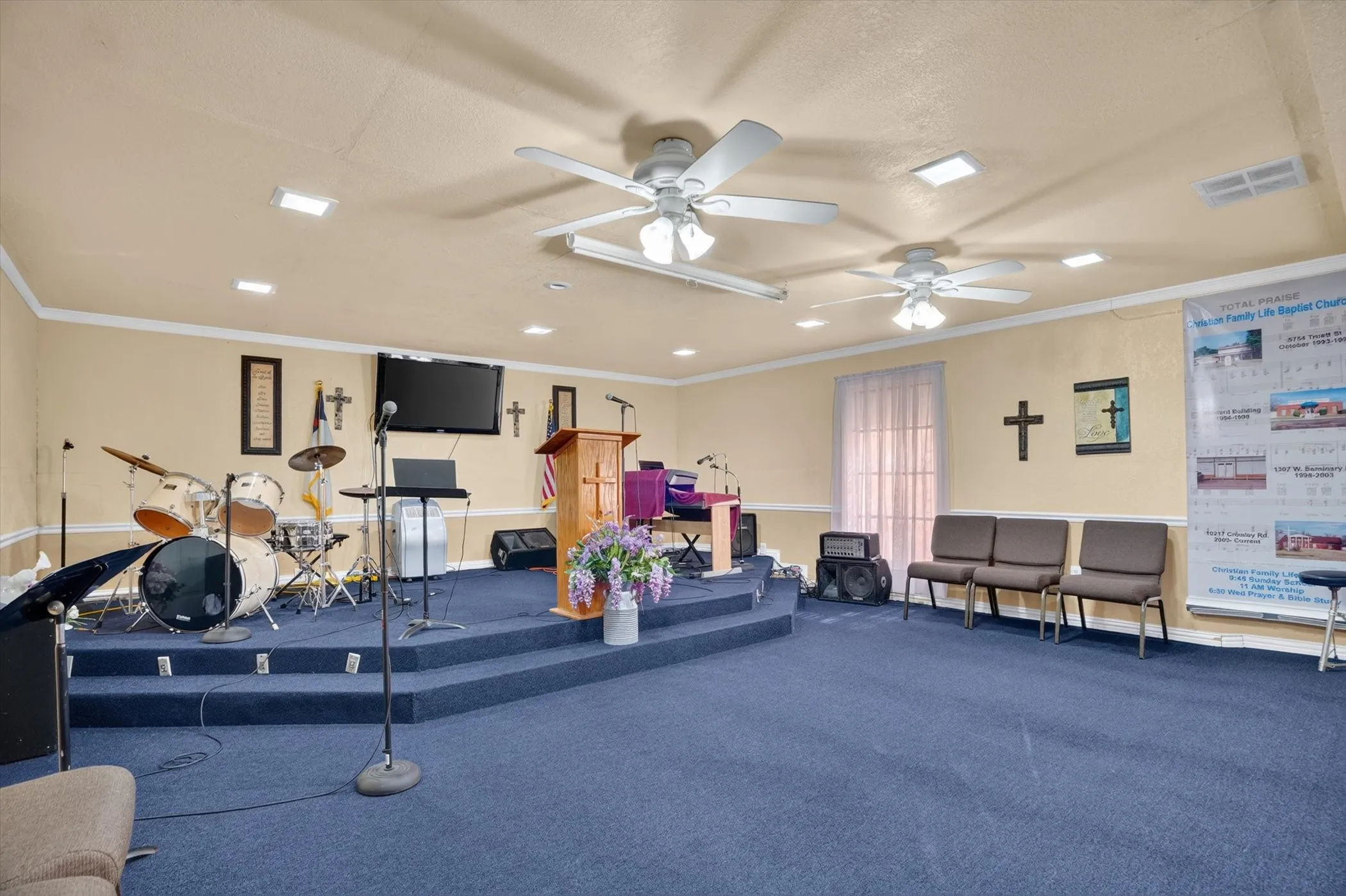 Spacious room featuring a raised platform with blue carpeting, recessed lighting, and multiple ceiling fans