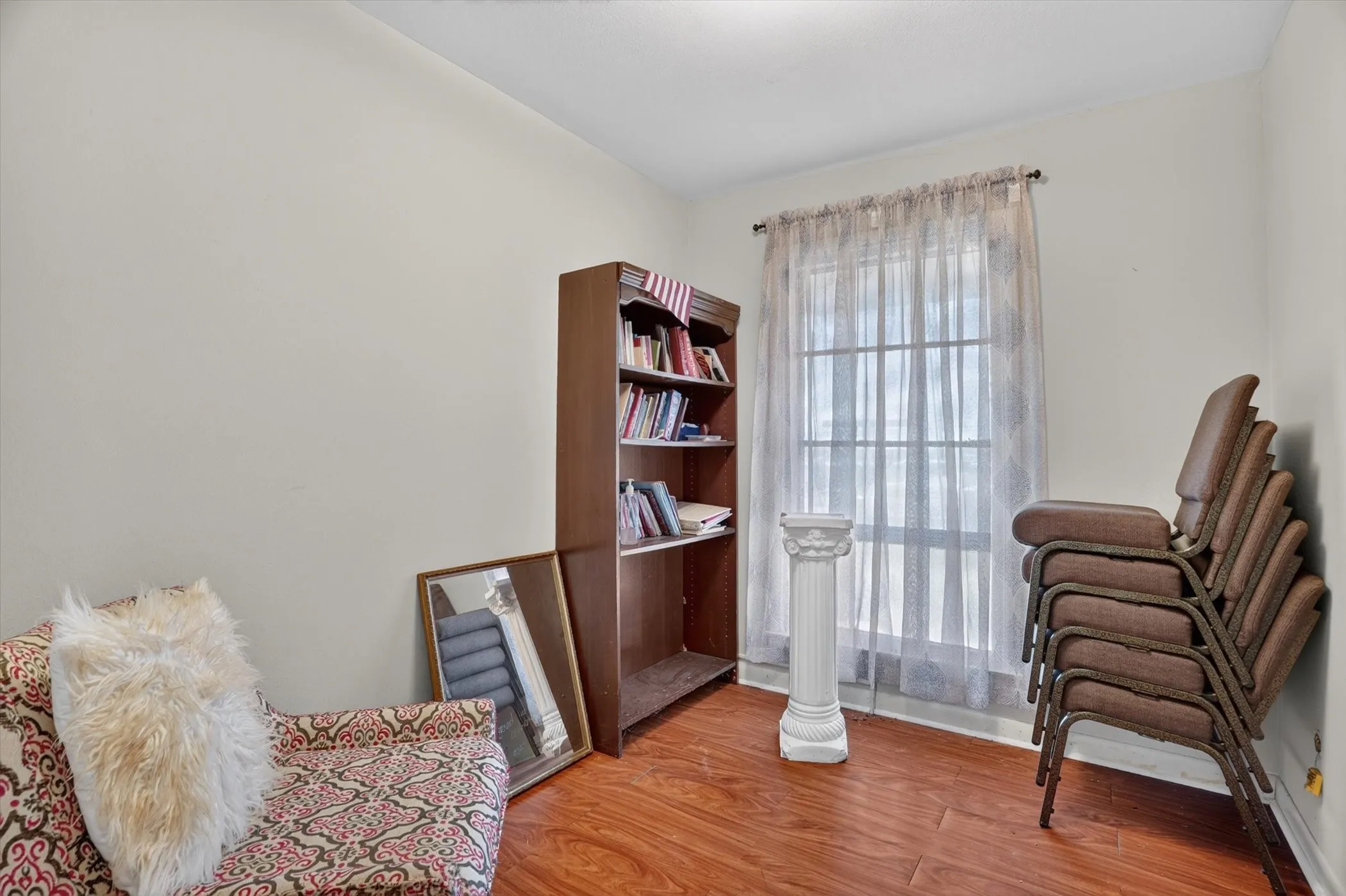 Interior room featuring wood-finish flooring, a window with sheer curtains, and light-toned walls