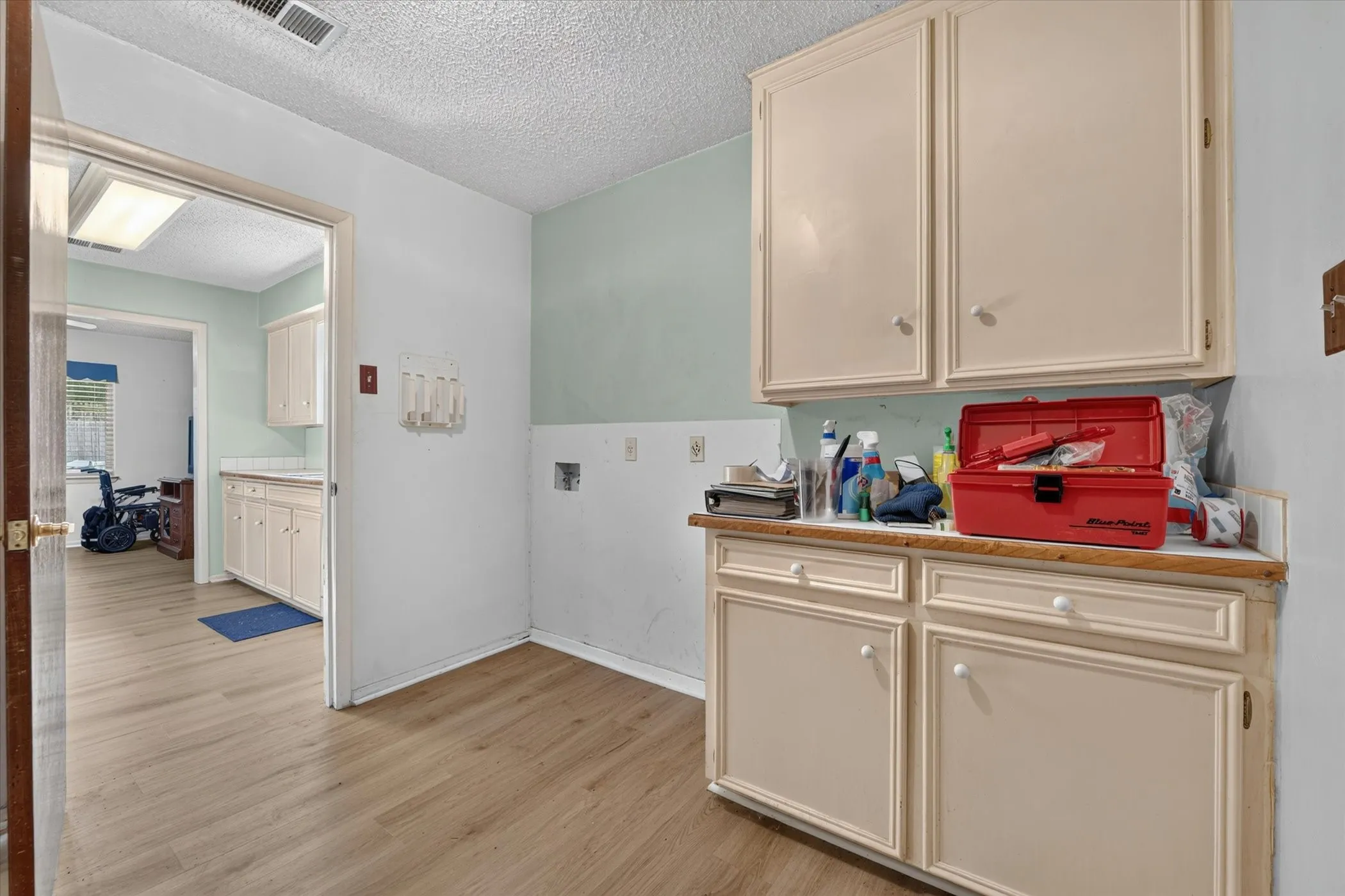 Utility area with wood-finish flooring, two-tone wall treatment, and built-in cabinetry with a countertop