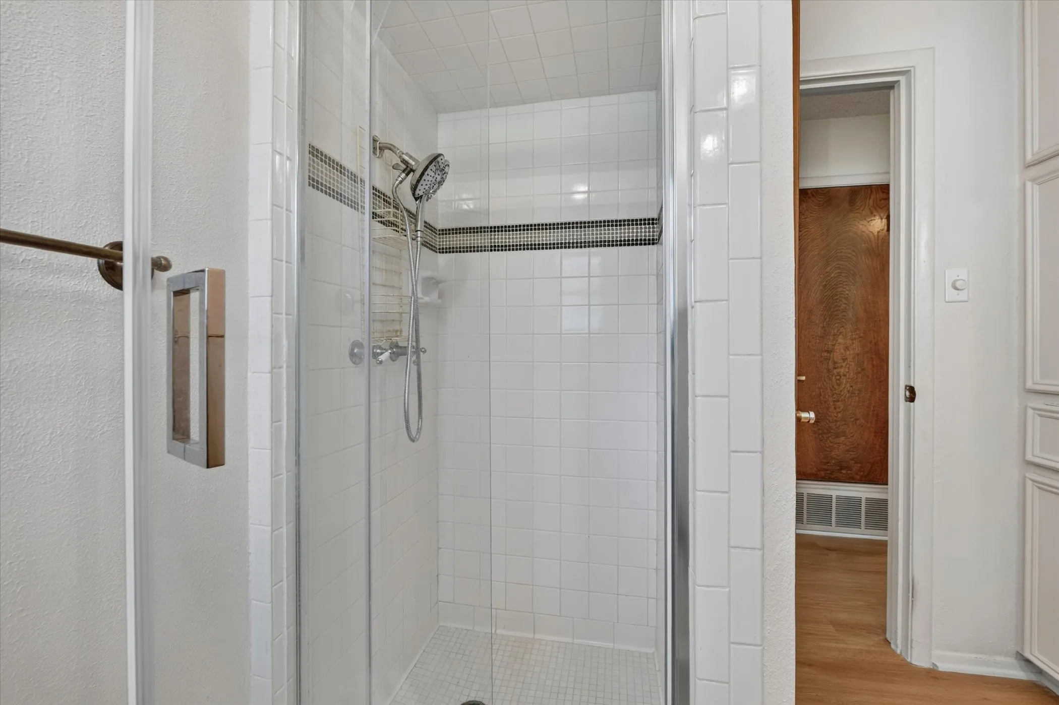 Glass-enclosed shower featuring white subway tile, mosaic accent tile, and a multi-function showerhead