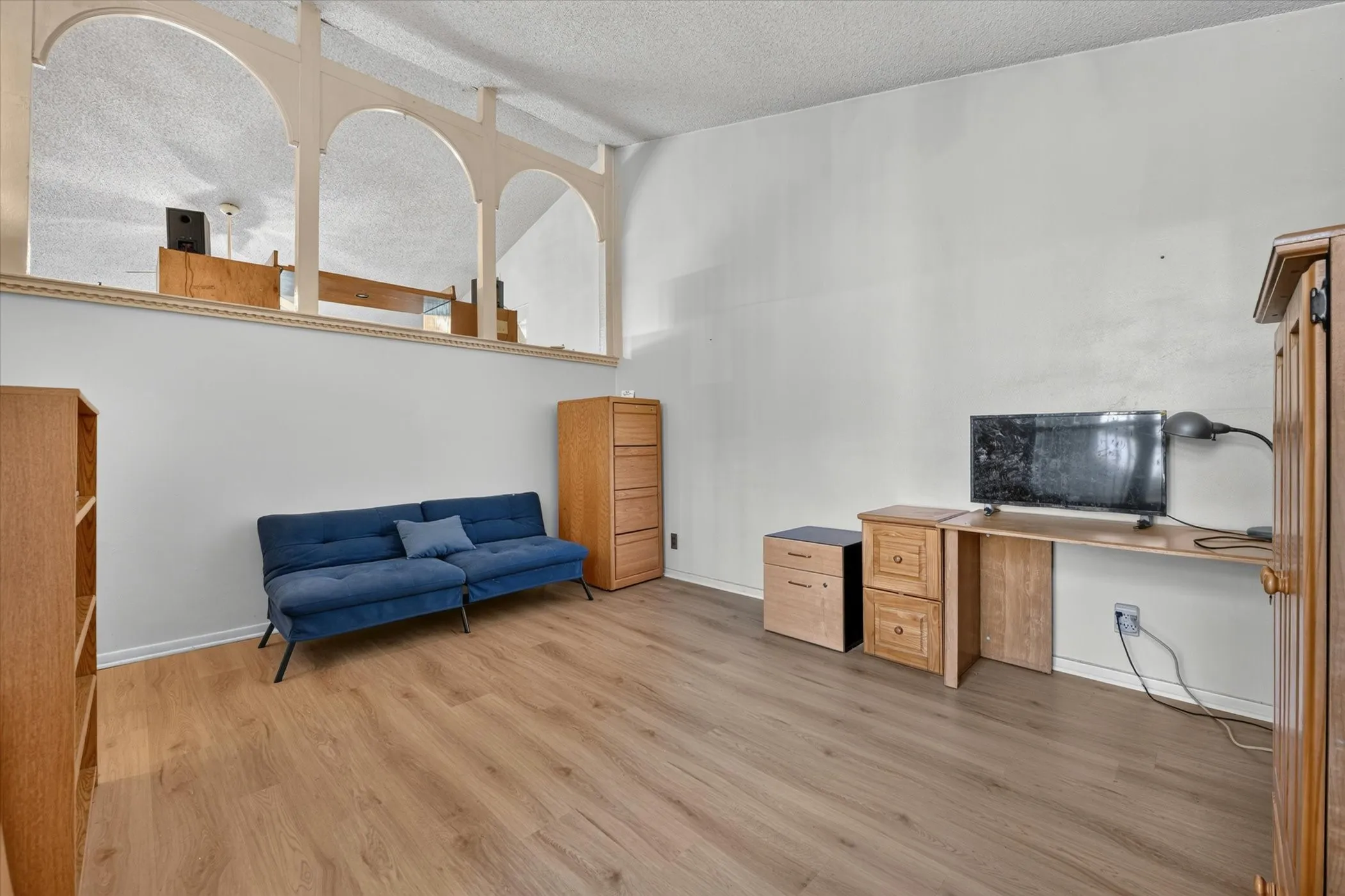 Open-concept room featuring wood-finish flooring, a neutral color palette, and a half-wall with decorative arch cutouts