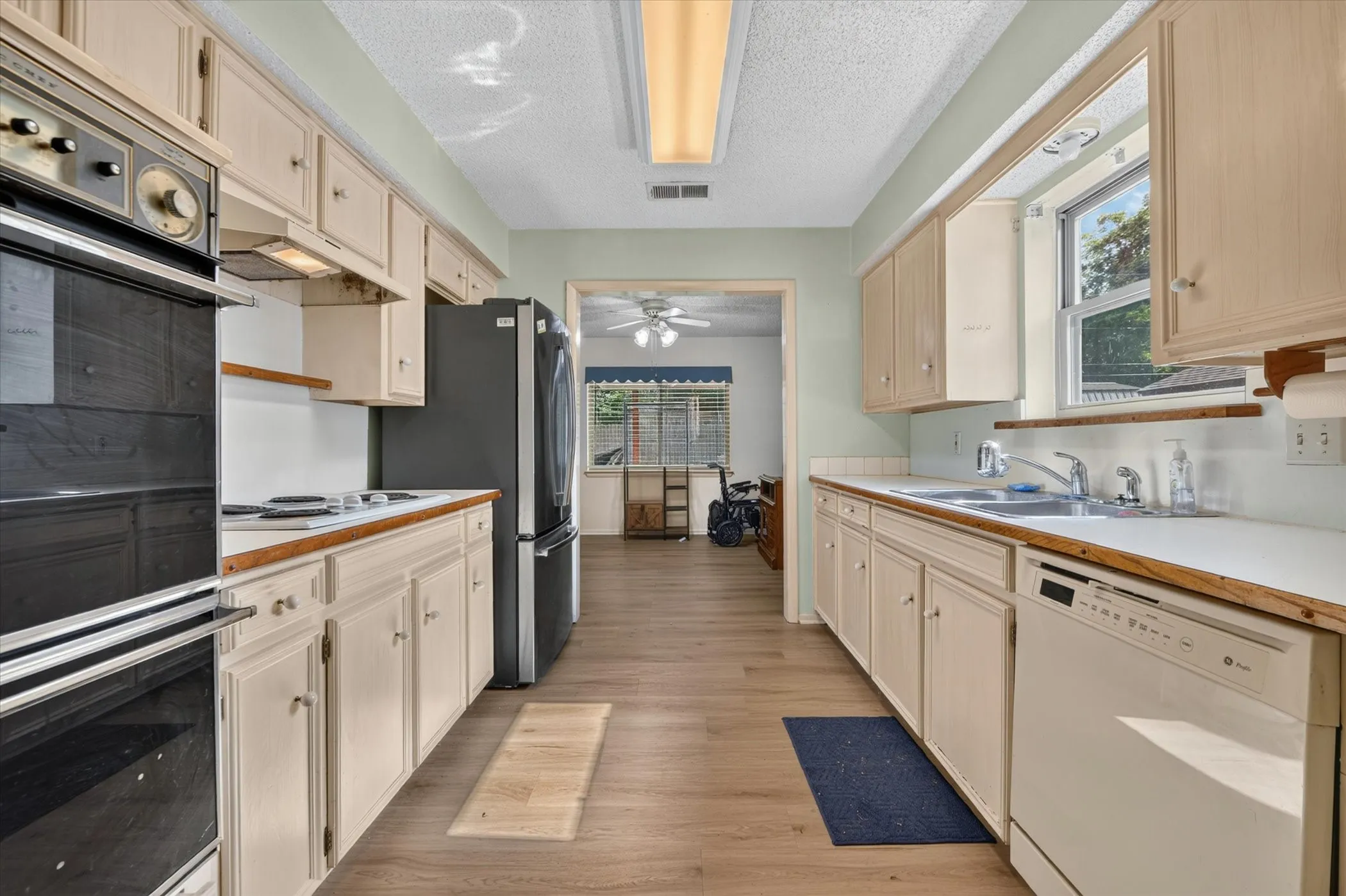 Galley kitchen featuring wood-finish flooring, light-toned cabinetry, and white countertops
