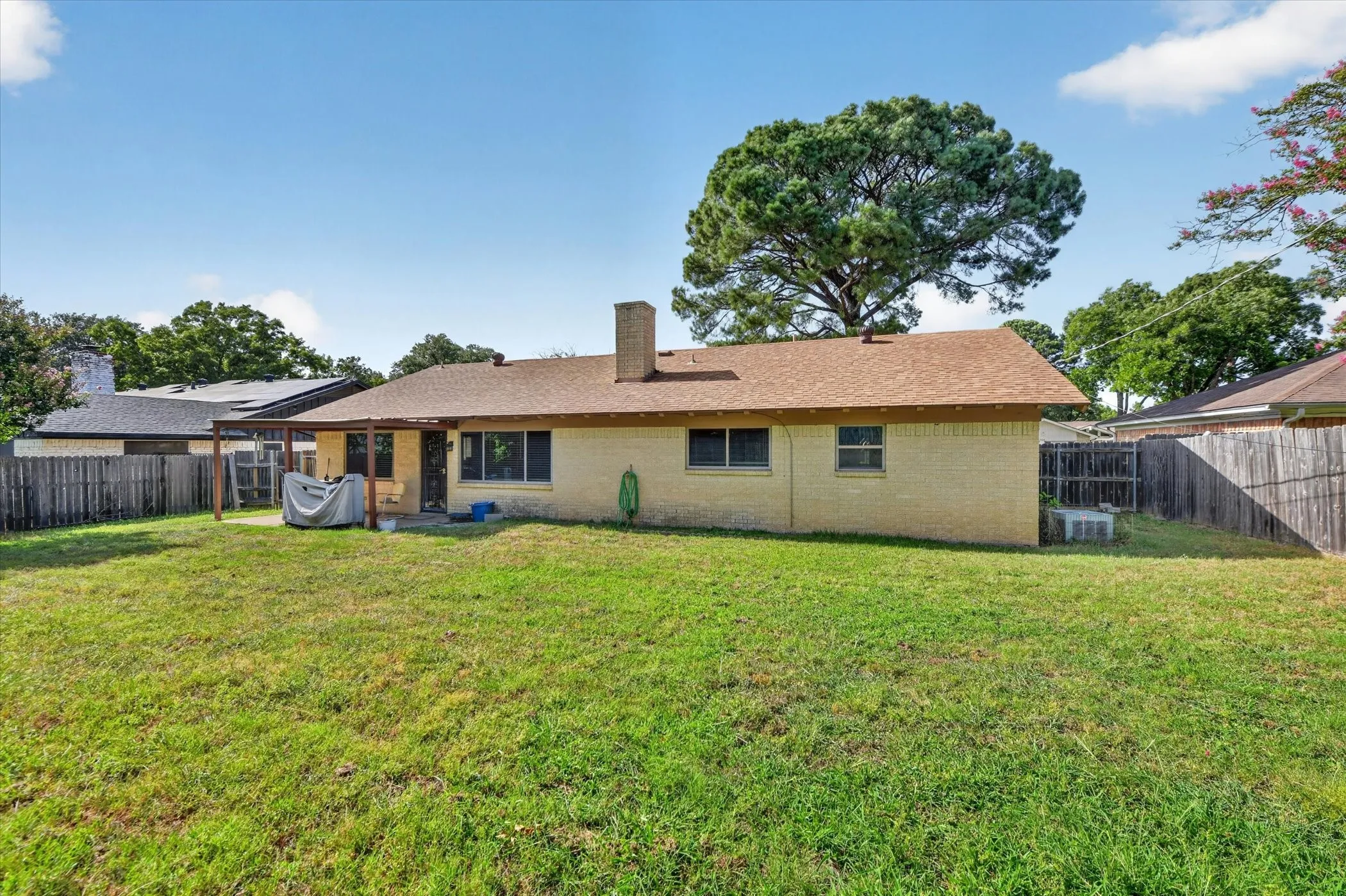 Expansive backyard featuring a manicured lawn and a covered patio area