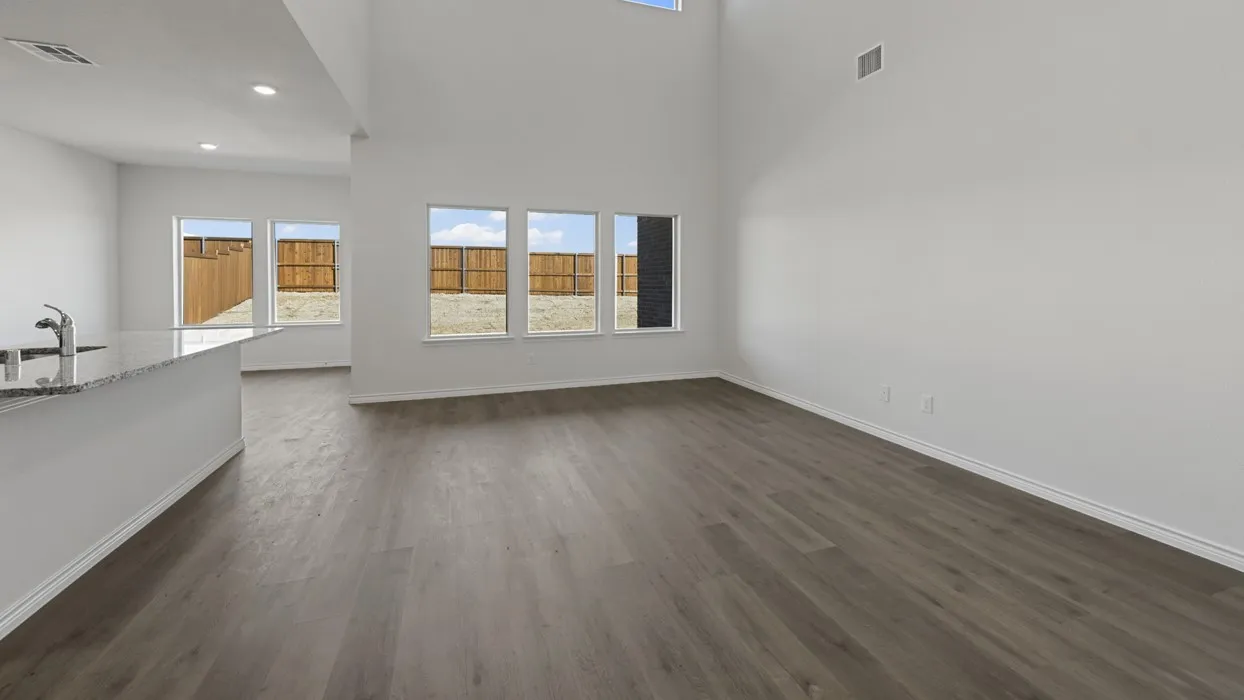 Expansive living area featuring high ceilings, wood-finish flooring, recessed lighting, and multiple windows