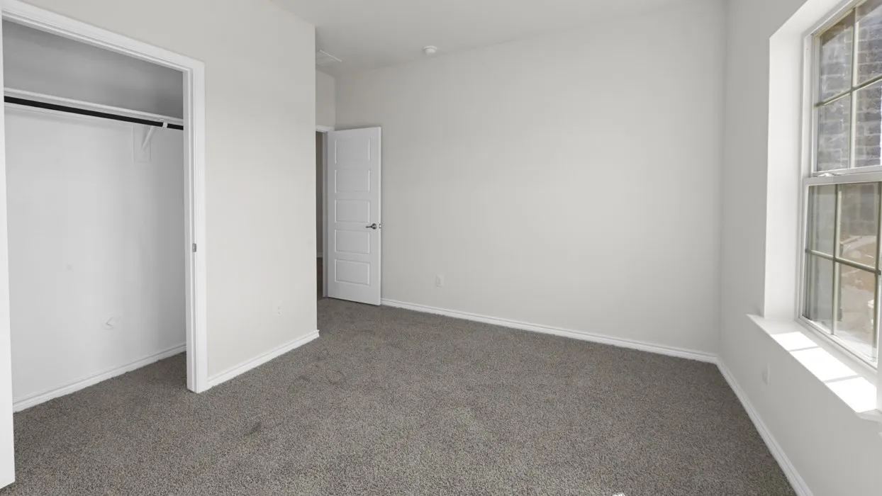 Carpeted room featuring a white paneled door, a window with grid panes, and a built-in closet with a hanging rod
