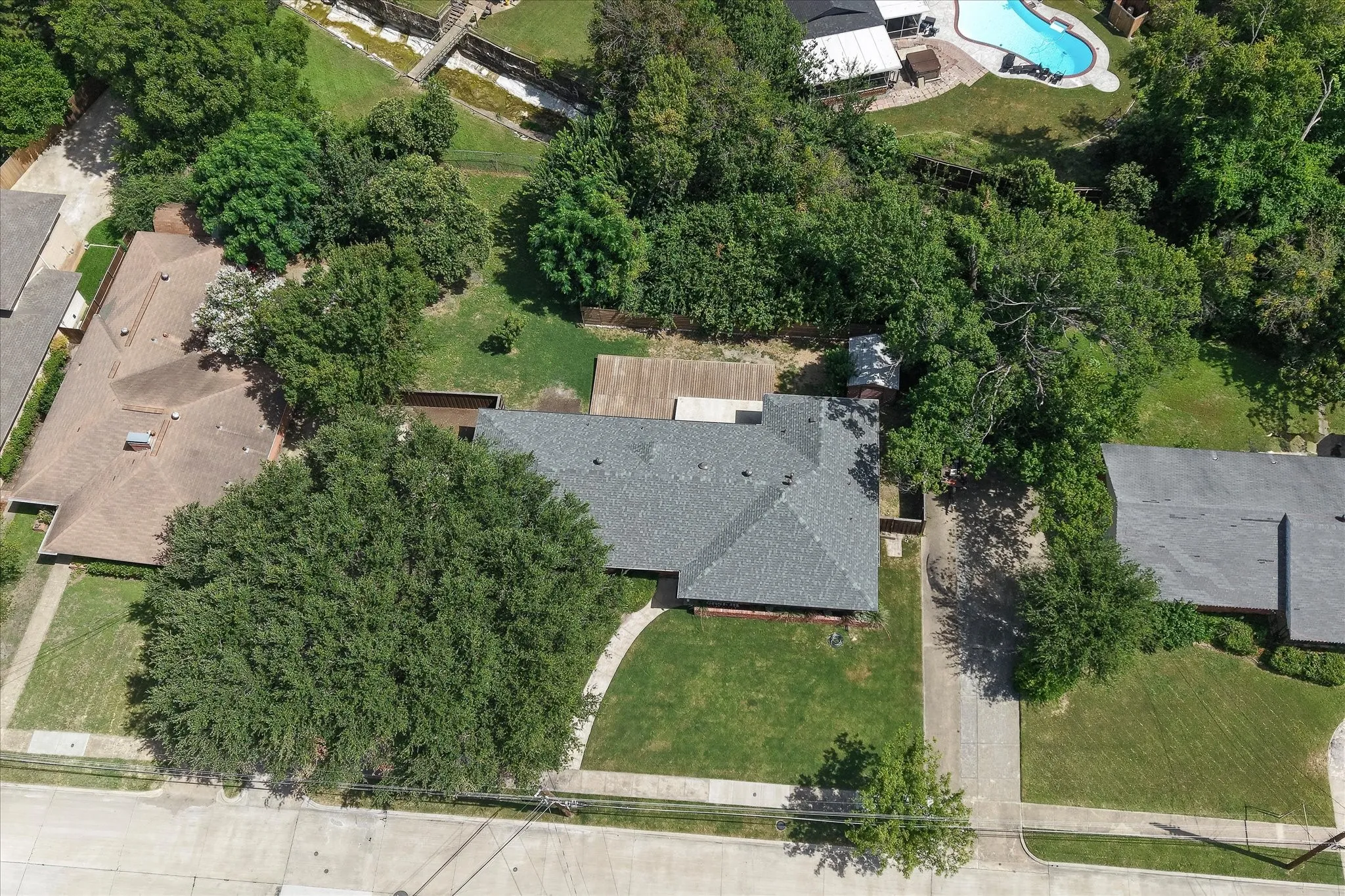 View of the new roof (just replaced in May of 2026), the gorgeous lot, trees, and peaceful creek in the background.