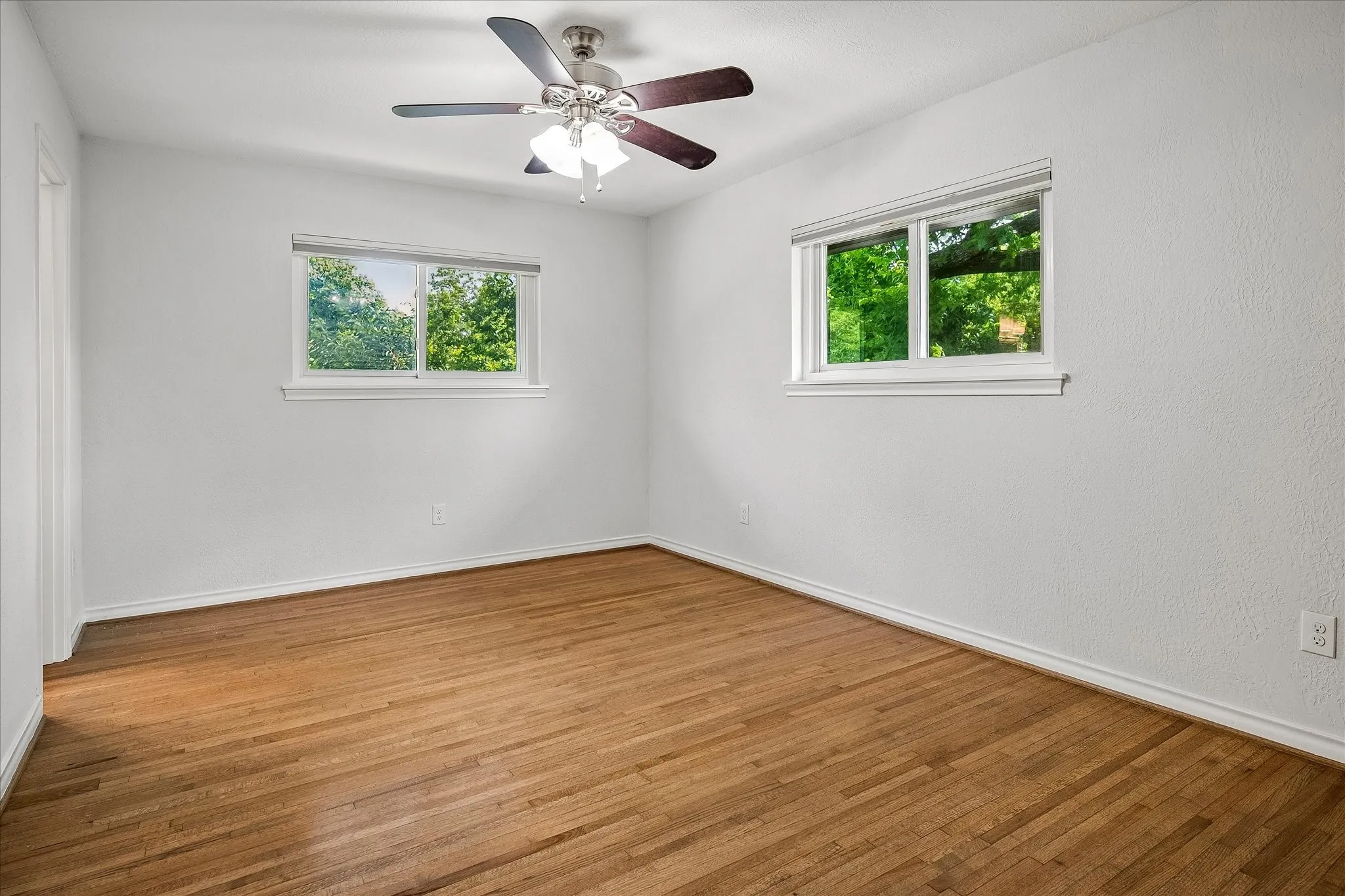Primary bedroom with double paned windows and cordless shades provding lovely light, views and the ability to open for fresh air or to hear the birds singing in the morning from your private backyard and small forest. You may even hear the creek running from time to time. Truly a unique lot providing the peacefulness of country life - yet in the heart of Dallas.