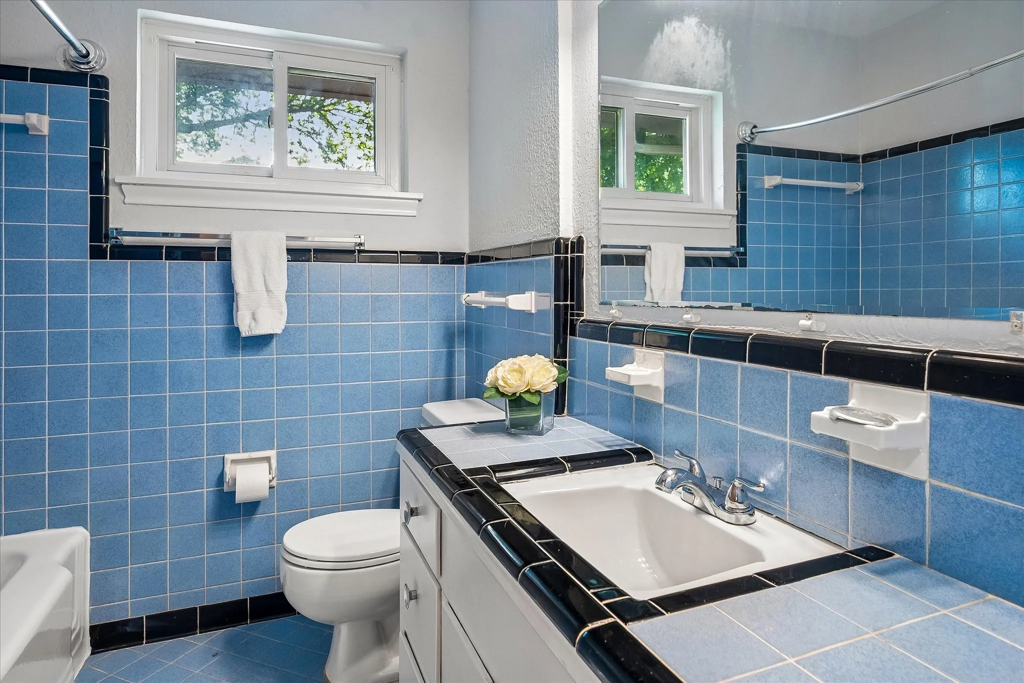 Hall bath with lovely original tile and cabinets. Bathtub has been refinished. Built in linen closet behind the door provides great storage space.