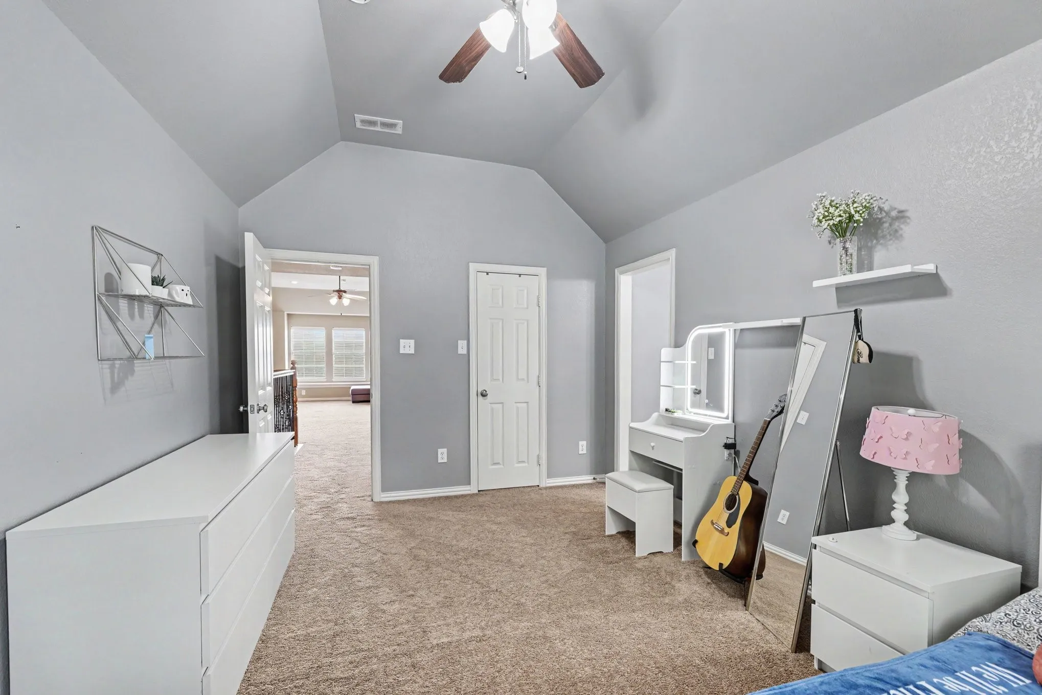 Carpeted room featuring a vaulted ceiling and a ceiling fan with integrated lighting