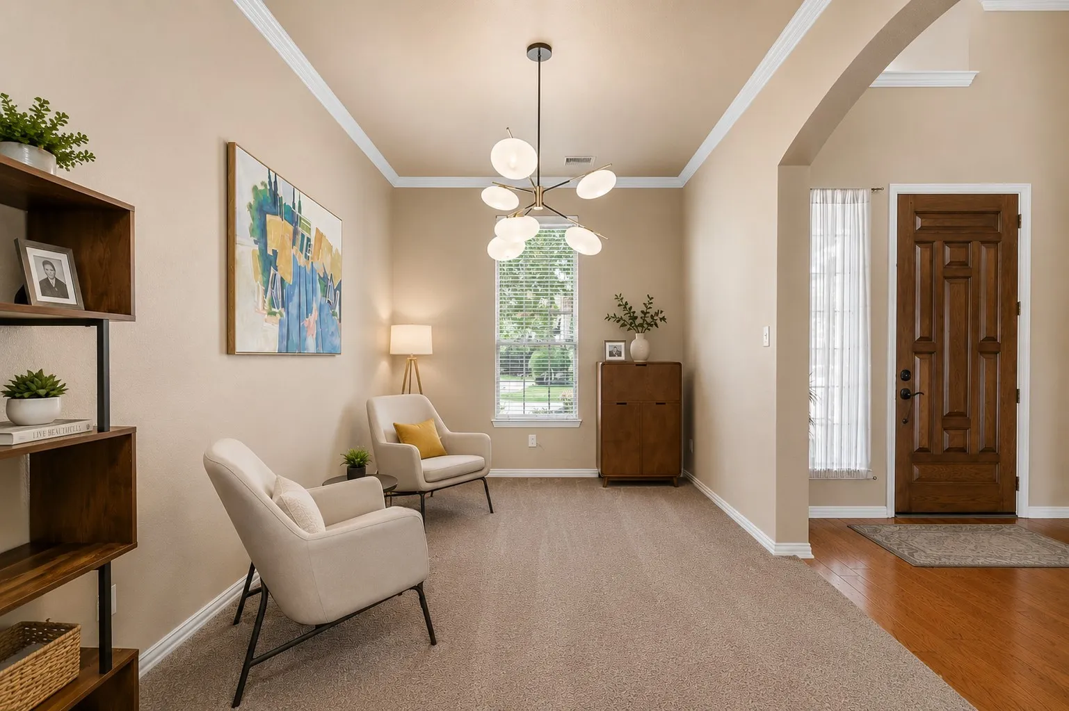 Archway entrance to a versatile living area featuring carpet flooring, crown molding, and a contemporary chandelier