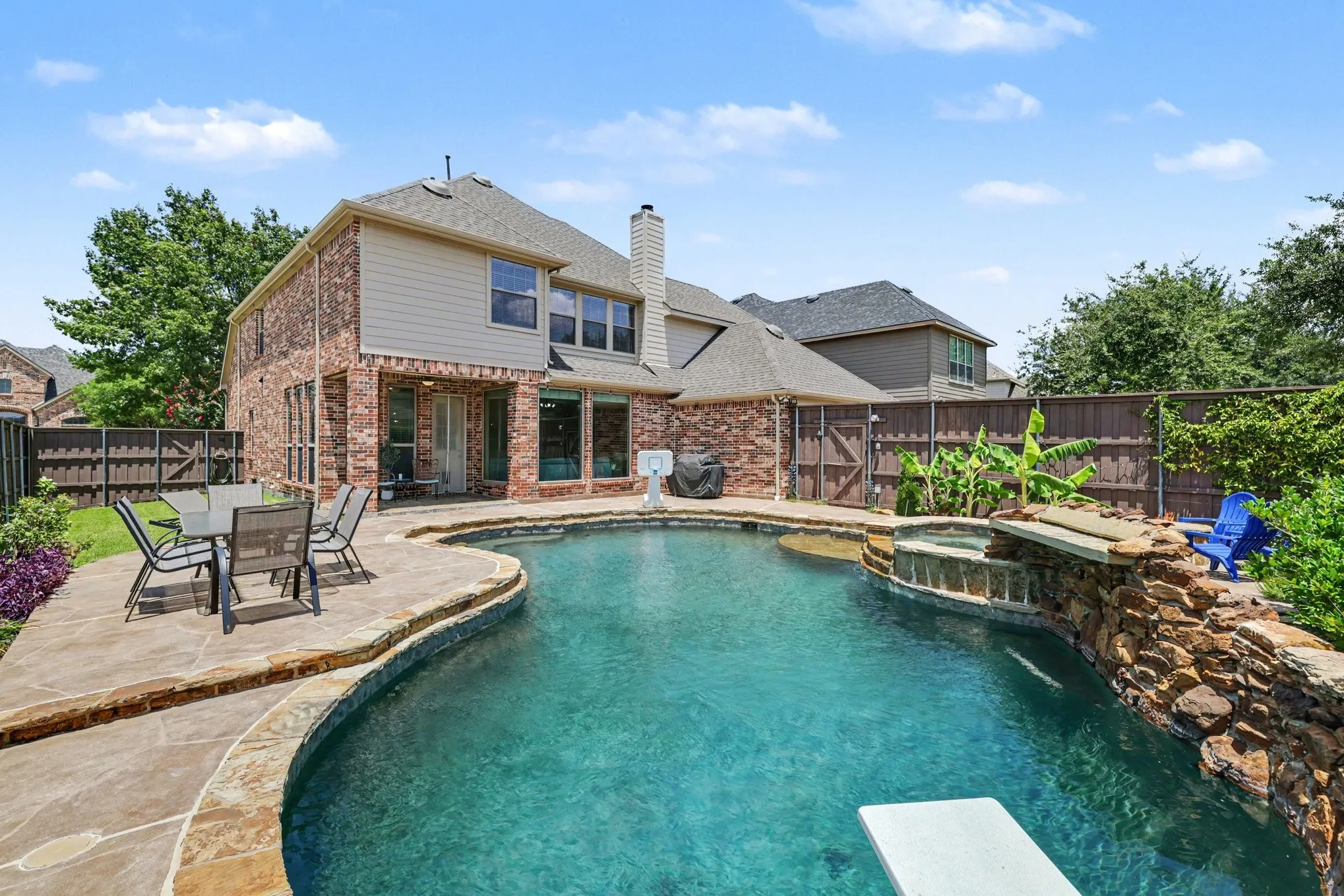 Backyard oasis featuring a curvilinear swimming pool, integrated spa with stone water feature, and flagstone coping