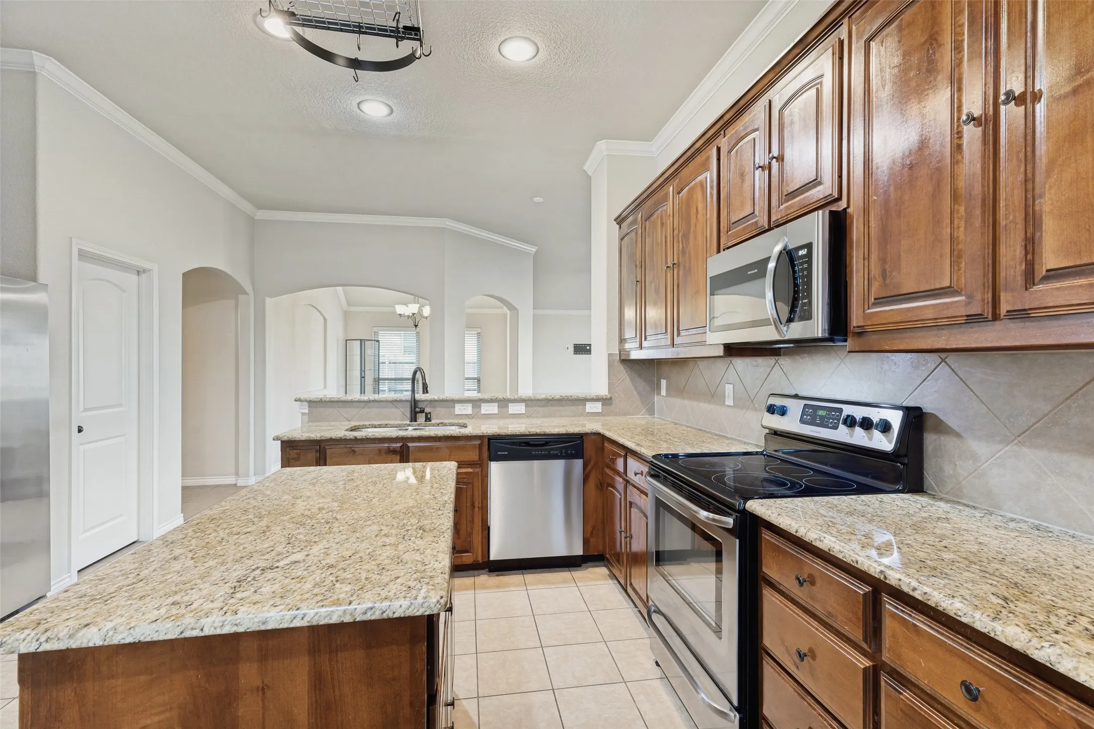 Kitchen featuring granite countertops, wood cabinetry, stainless steel appliances, and tile flooring