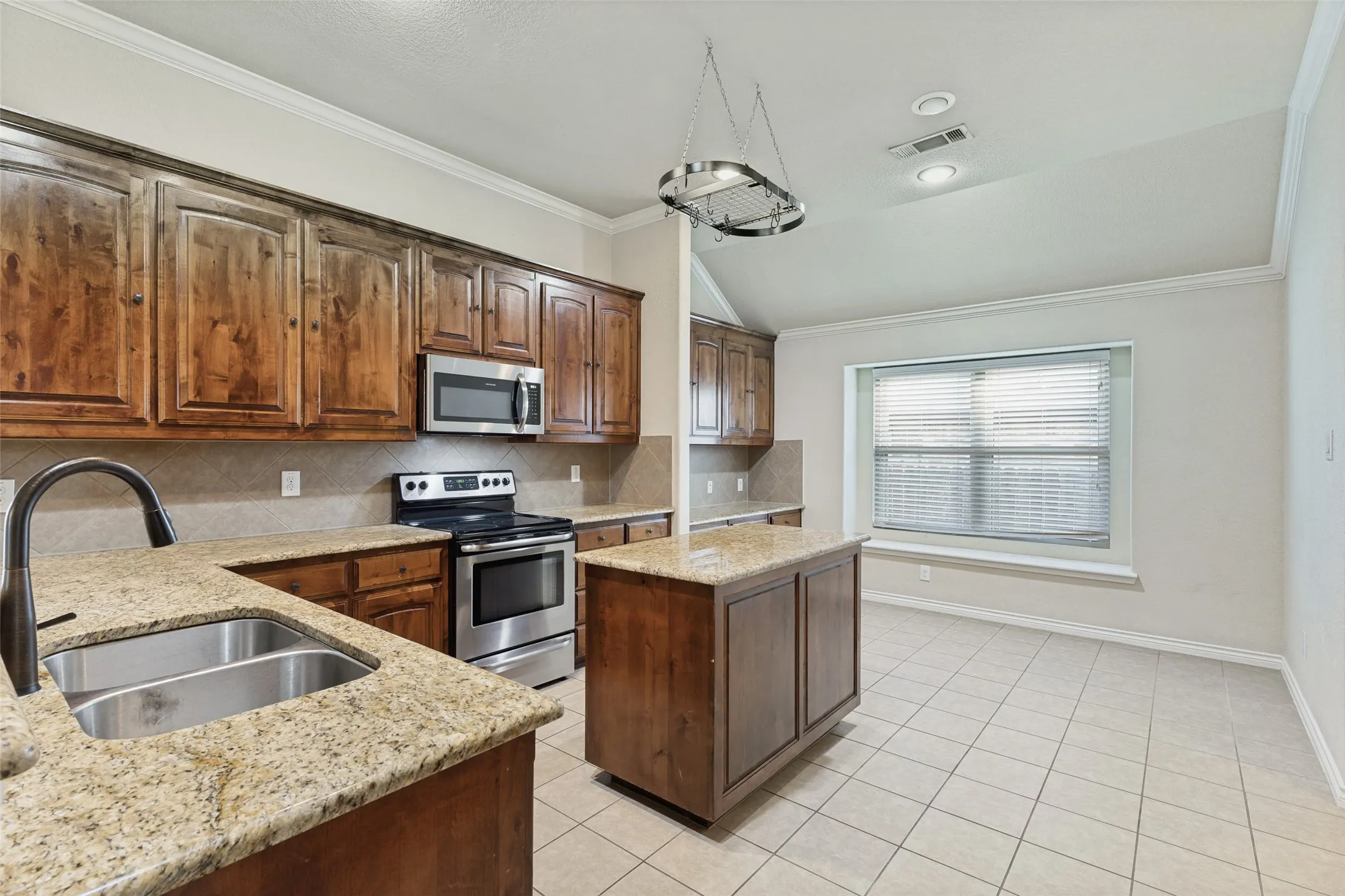 Kitchen featuring wood cabinetry, granite countertops, a stainless steel appliance suite, and a central island