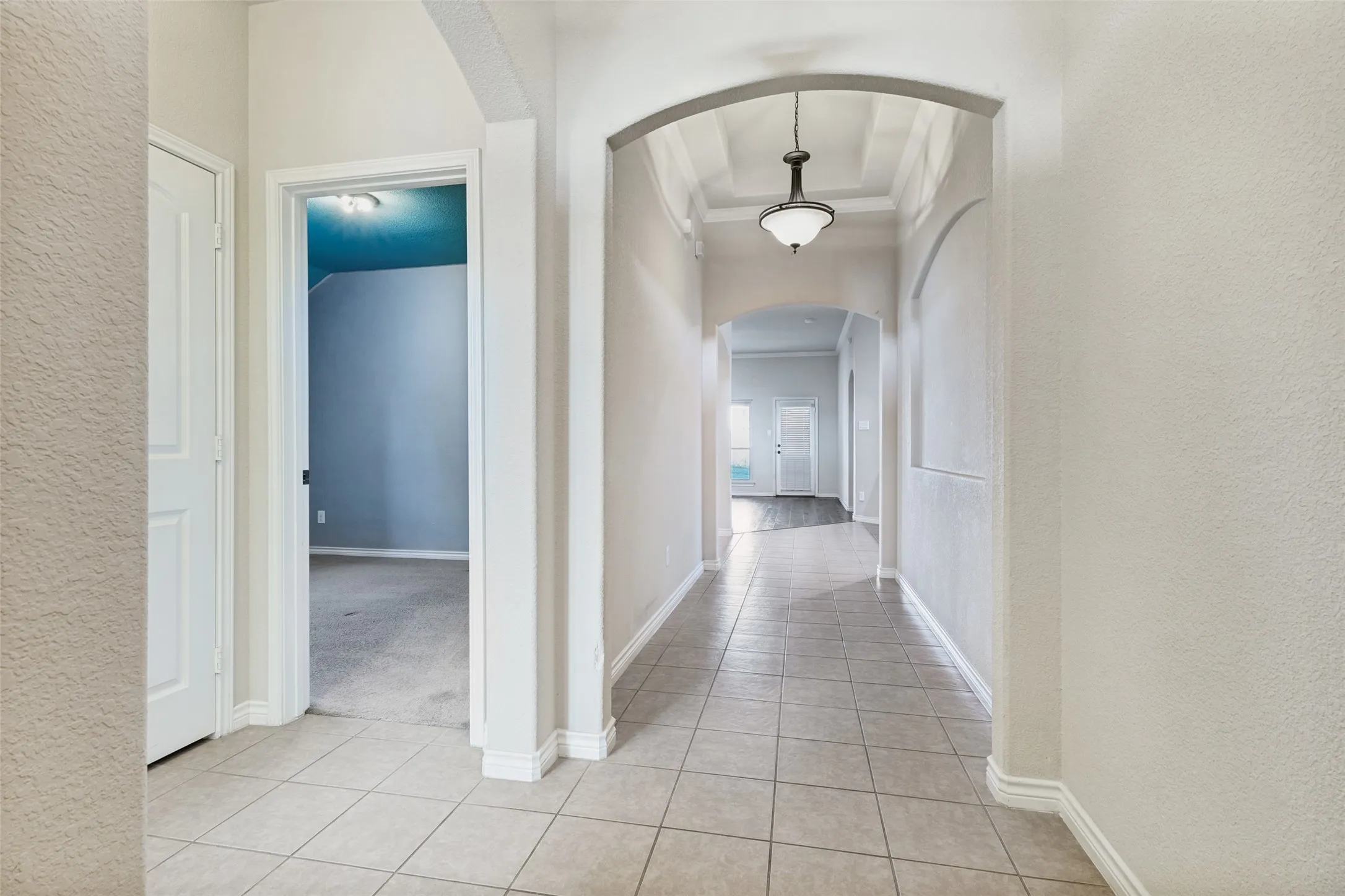Entryway featuring square tile flooring, arched doorways, a coffered ceiling, and a hanging pendant light fixture