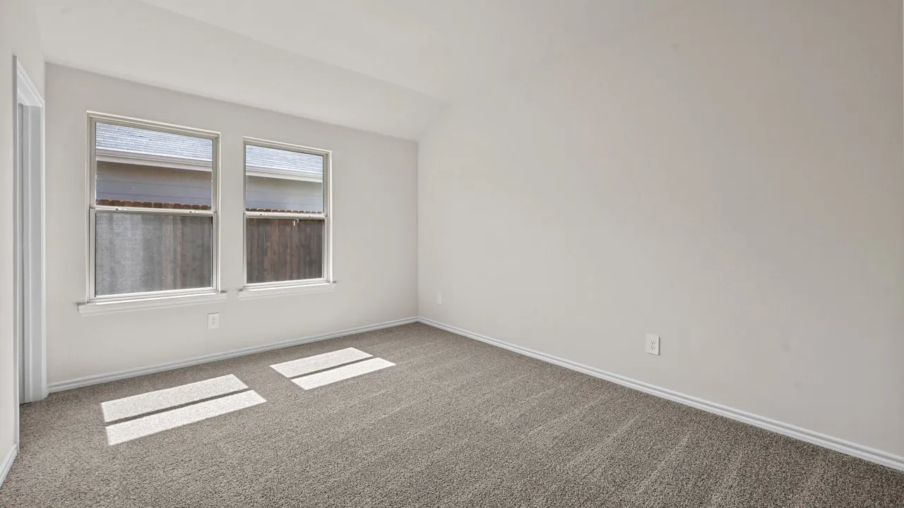 Carpeted room featuring two double-hung windows, light-toned wall paint, white trim, and a vaulted ceiling