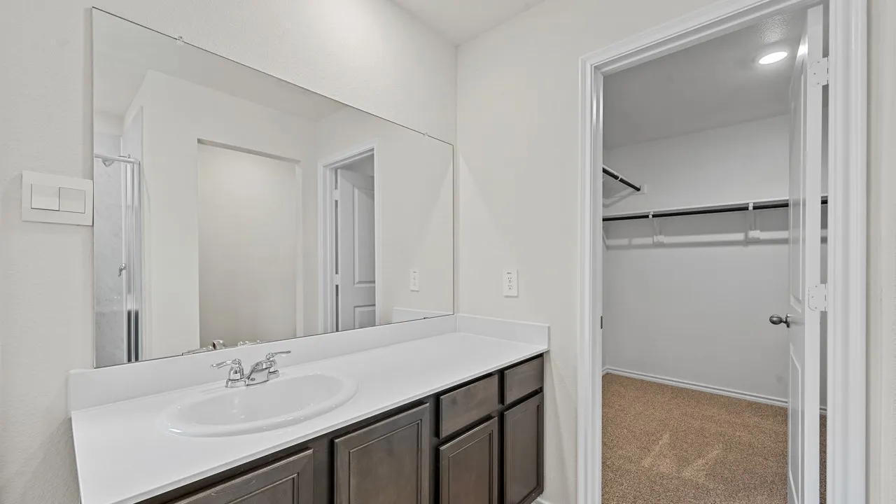 Bathroom vanity featuring an integrated sink, polished chrome faucet, and a large wall-mounted mirror
