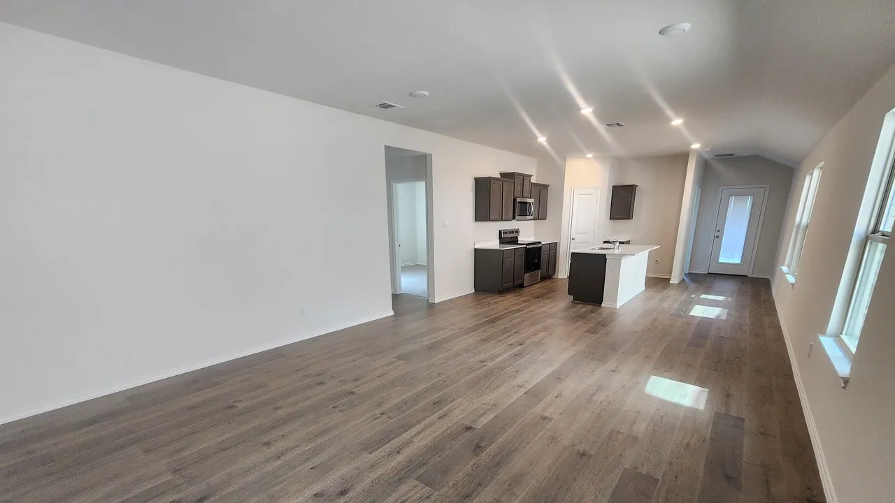 Open-concept living area featuring wood-finish flooring, recessed lighting, and a vaulted ceiling