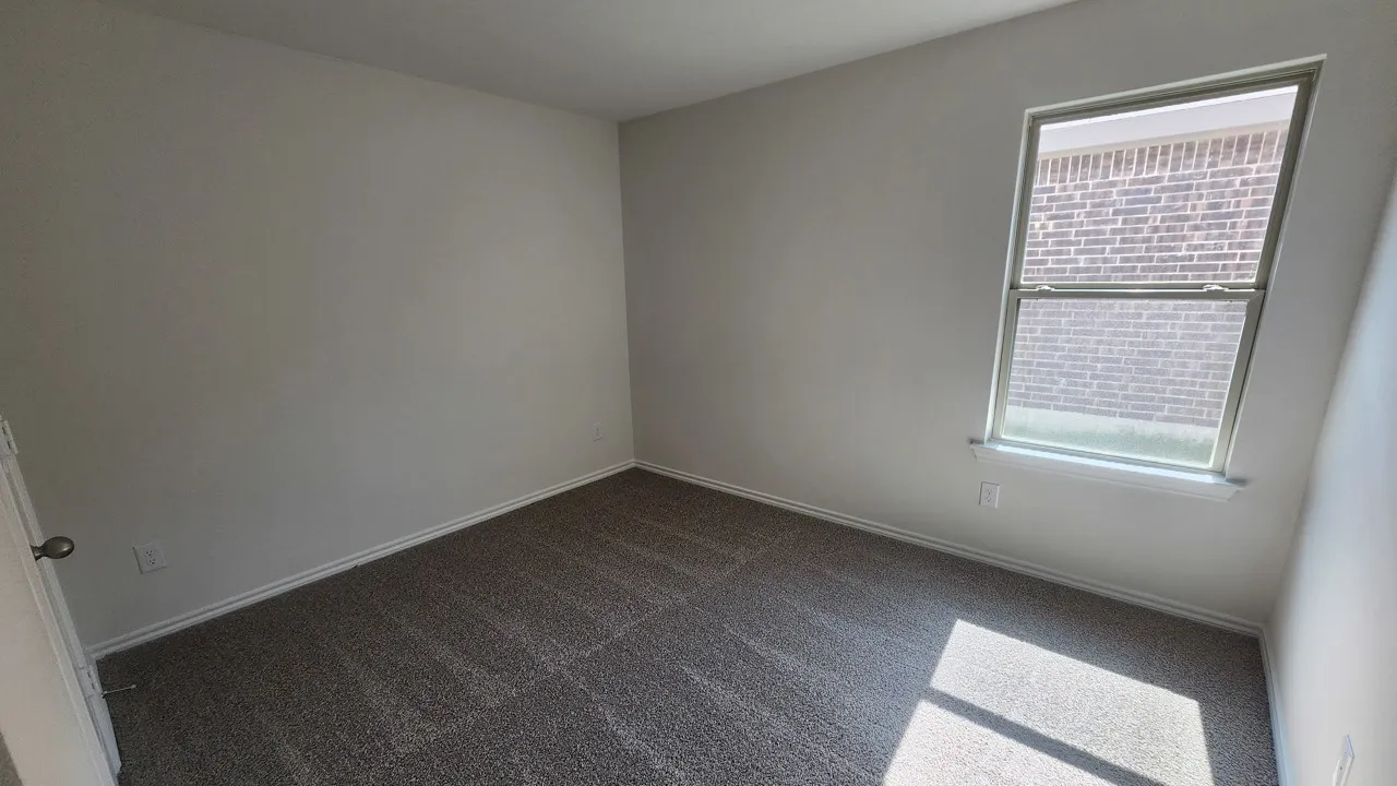 Bedroom featuring neutral wall paint, gray patterned carpeting, a single window with white trim, and a white baseboard