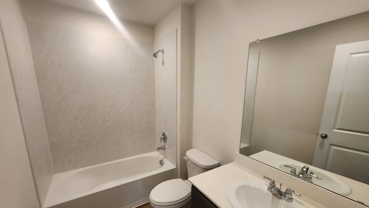 Bathroom featuring a tub/shower combination with a textured surround, single vanity with a white countertop, undermount sink, and a large wall-mounted mirror