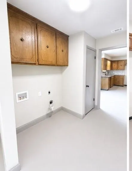Dedicated utility area featuring overhead wood cabinetry and light-colored flooring