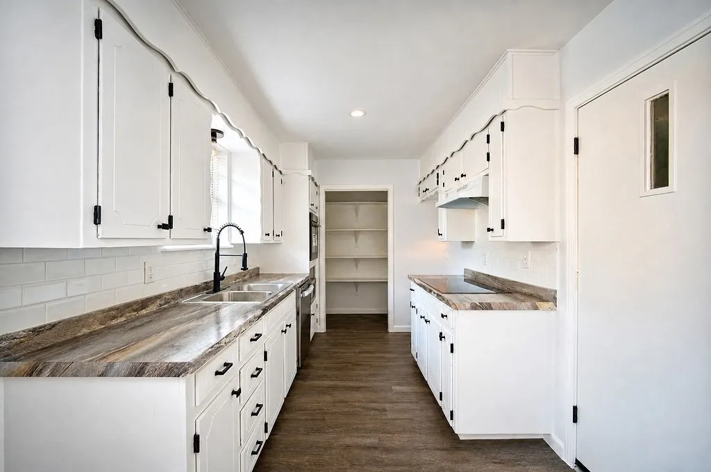 Galley kitchen featuring white cabinetry, wood-finish flooring, and light-toned countertops