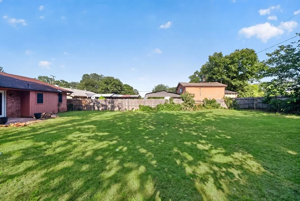 Expansive backyard featuring a lush lawn and perimeter wood fencing