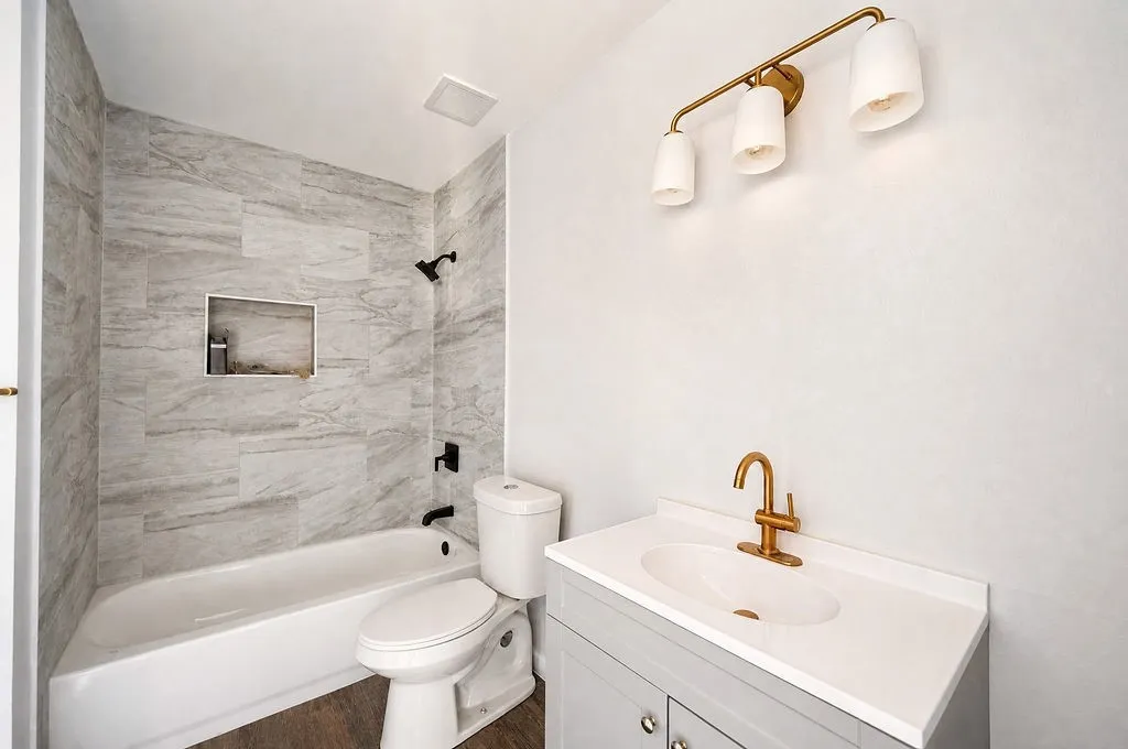 Bathroom featuring a white tub, shower with a tiled surround and built-in niche, and matte black fixtures