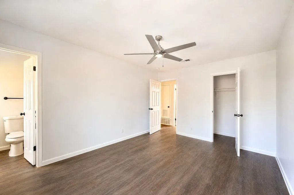 Spacious room featuring wood-finish flooring, white walls, and a contemporary ceiling fan with integrated lighting