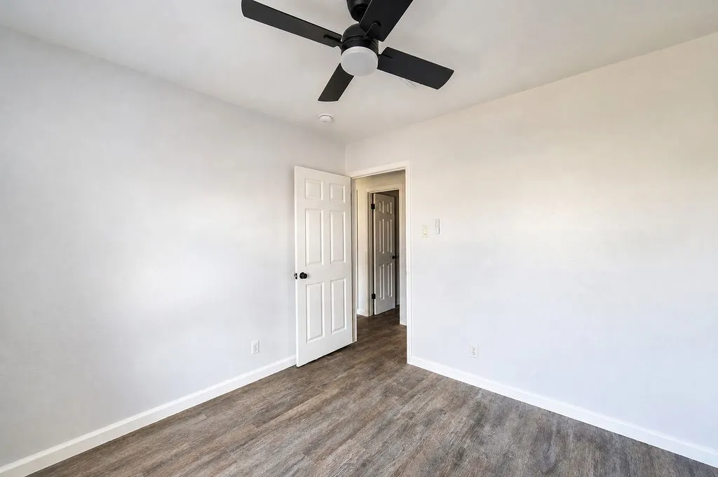 Room featuring wood-finish flooring, white baseboards, and light-toned walls
