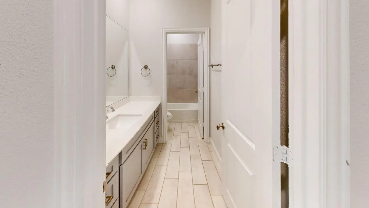Bathroom vanity featuring dual undermount sinks, a light-toned countertop, and gray cabinetry with brass hardware