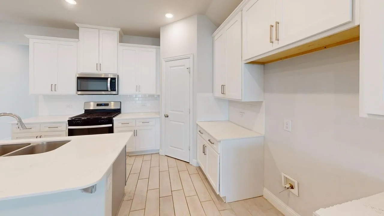 Contemporary kitchen featuring white cabinetry, light-toned countertops, and wood-finish tile flooring