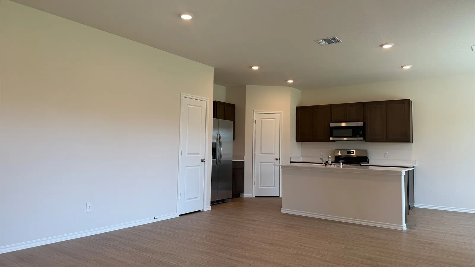 Open-concept living area featuring wood-finish flooring, recessed lighting, and a kitchen island with a light-toned countertop