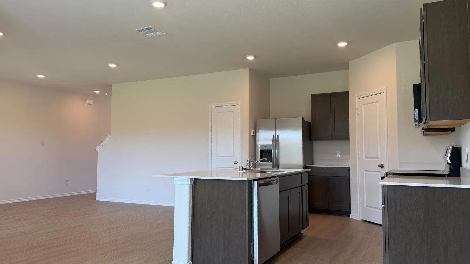 Open-concept living space featuring wood-finish flooring, recessed lighting, and a kitchen island with seating